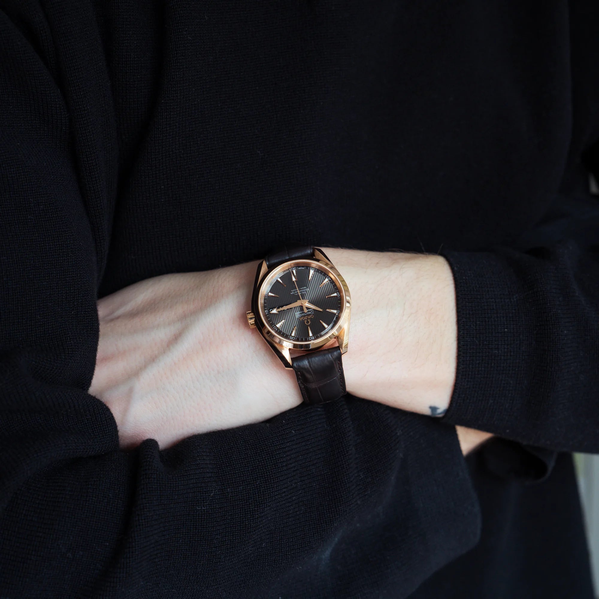 Mann trägt die Omega Seamaster Aqua Terra Annual Calender mit rosségoldenem Gehäuse an seinem Handgelenk und verschränkt seine Arme vor seinem Körper
