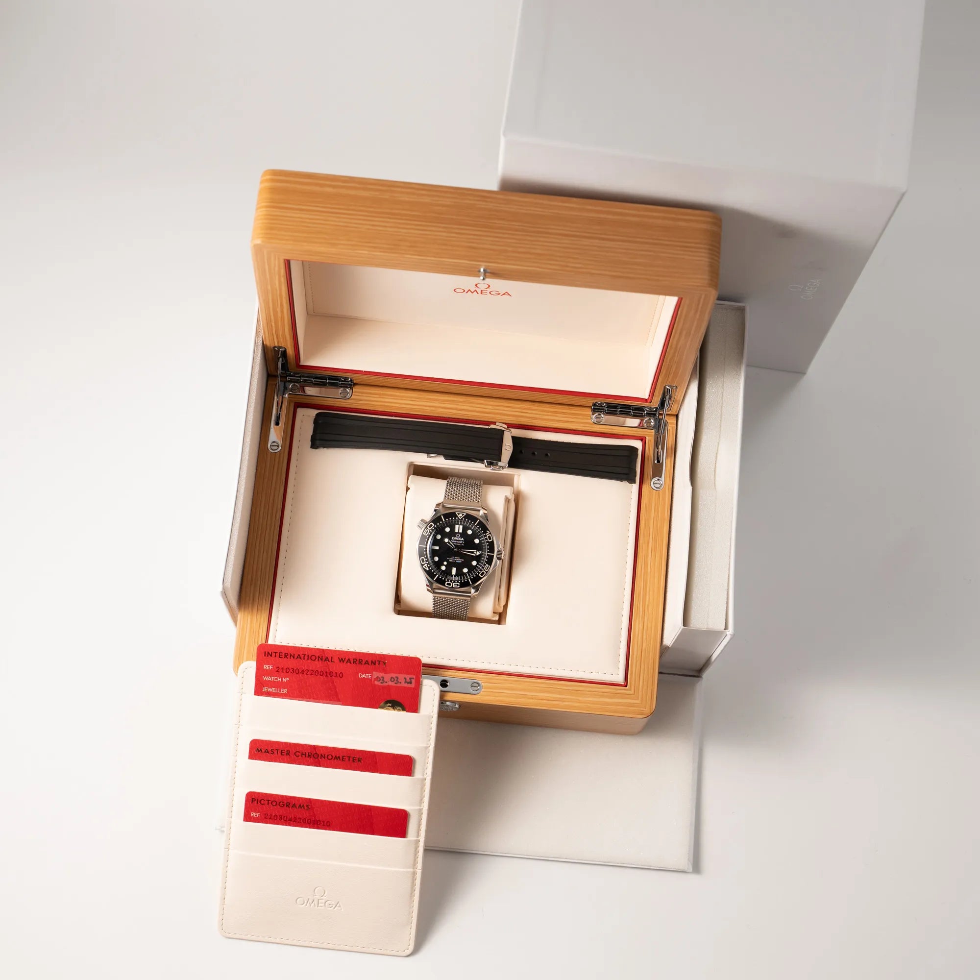 Omega Seamaster 300M Diver 210.30.42.20.01.010 mit dems schwarzen Zifferblatt im Wellen-Design am Milanese-Edelstahl-Armband zusammen mit dem Lieferumfang, bestehend aus Box mit Umkarton, einem zusätzlichen schwarzen Kautschuk-Armband, der Bedienungsanleitung, sowie allen Garaniekarten