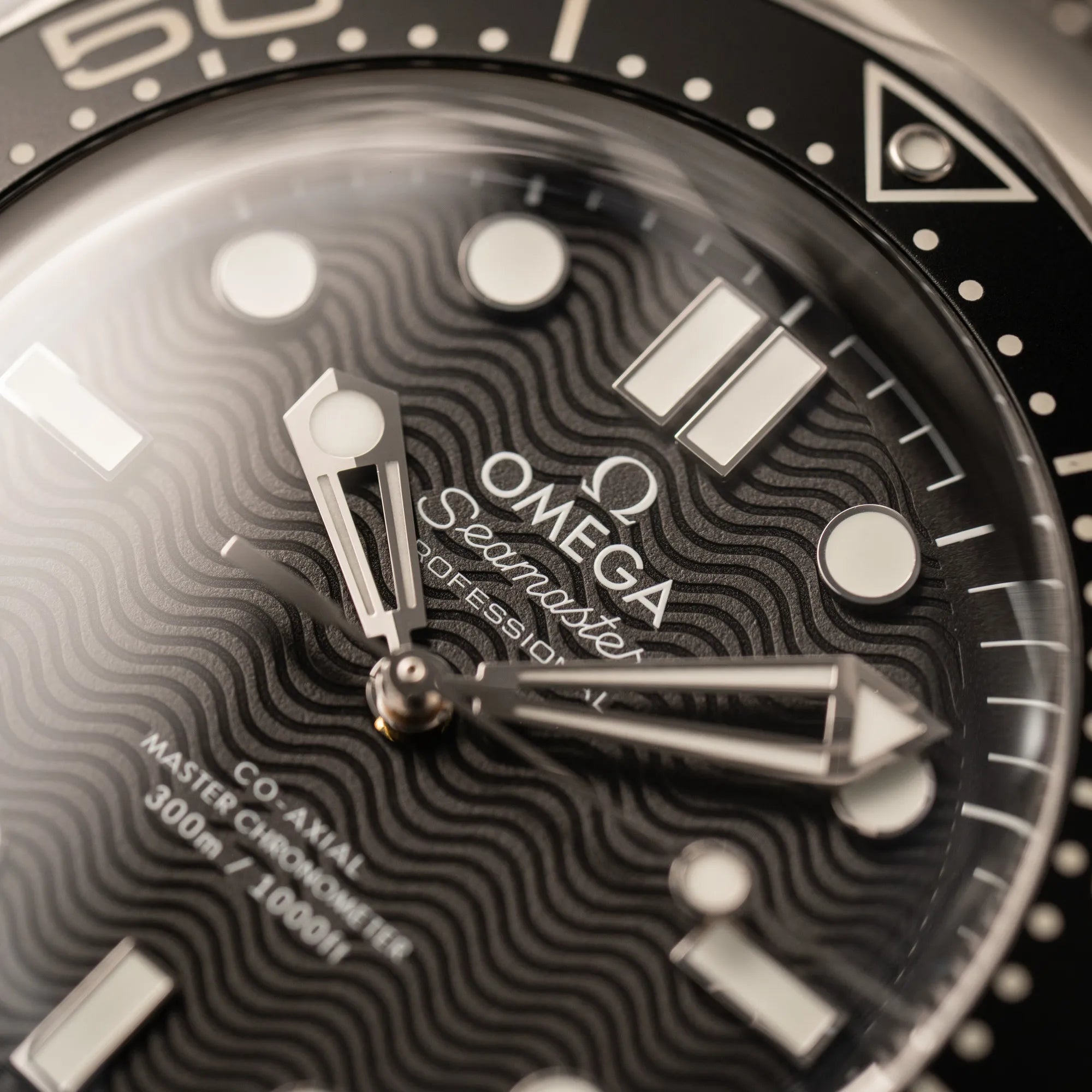 Makroaufnahme des Omega Seamaster Professional Schrifzugs von der Omega Seamaster 300M Diver 210.30.42.20.01.010 mit dems schwarzen Zifferblatt im Wellen-Design am Milanese-Edelstahl-Armband