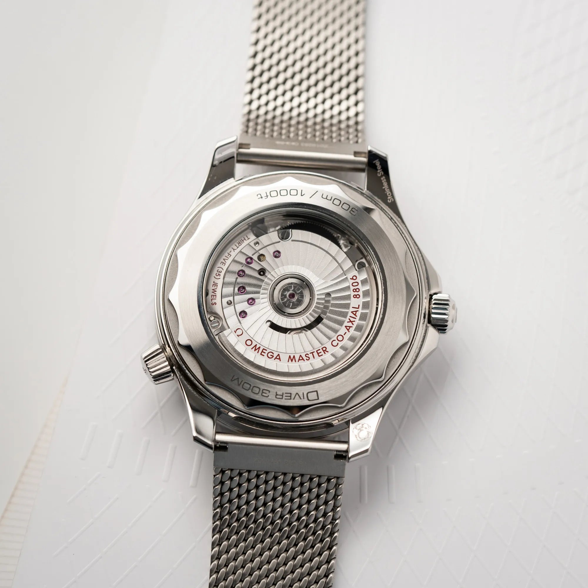 Glasboden der Omega Seamaster 300M Diver 210.30.42.20.01.010 mit dems schwarzen Zifferblatt im Wellen-Design am Milanese-Edelstahl-Armband mit Blick auf das automatische Uhrwerk Cal 8806