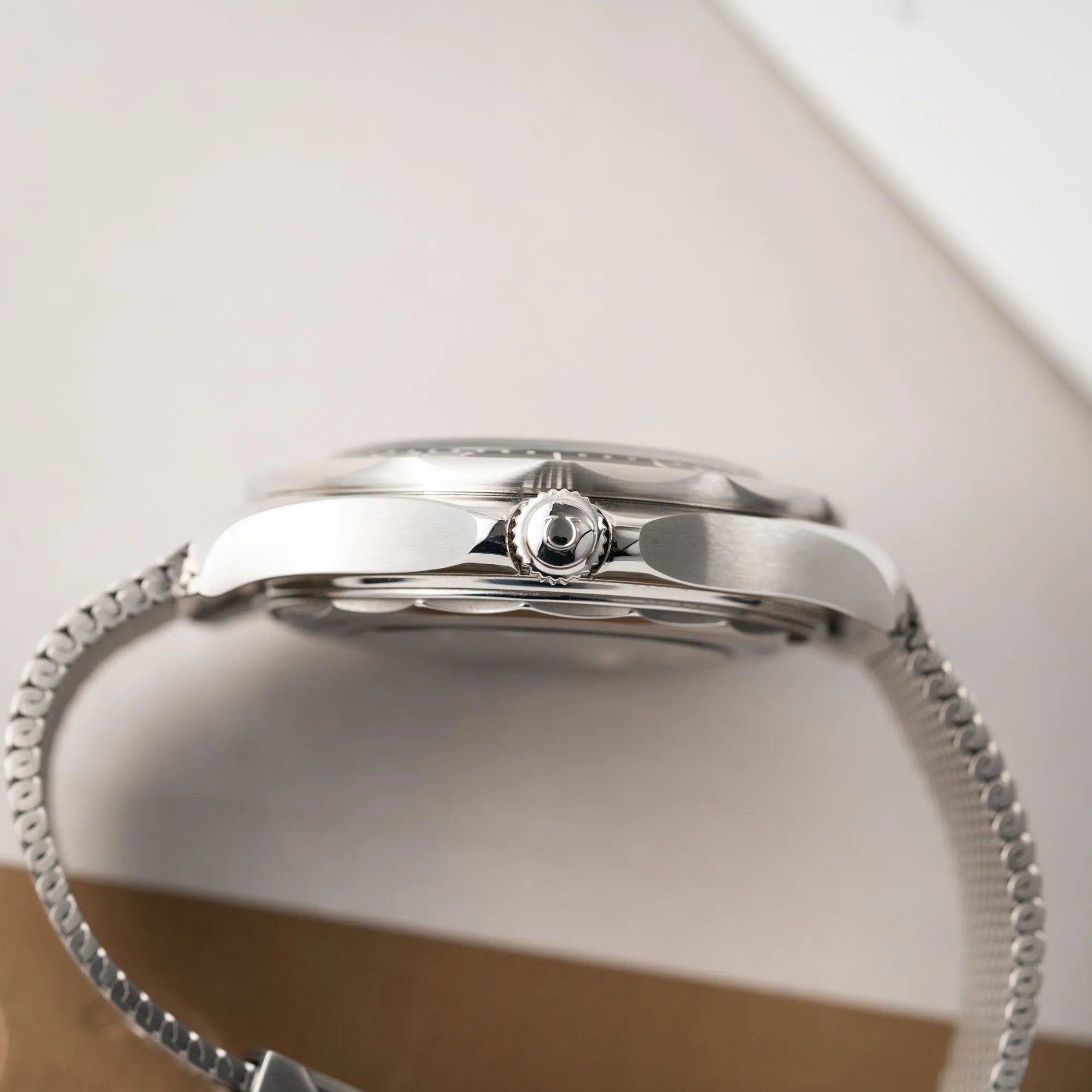 Seitliche Gehäuseflanke der Omega Seamaster 300M Diver 210.30.42.20.01.010 mit dems schwarzen Zifferblatt im Wellen-Design am Milanese-Edelstahl-Armband zeigt die Aufzugskrone