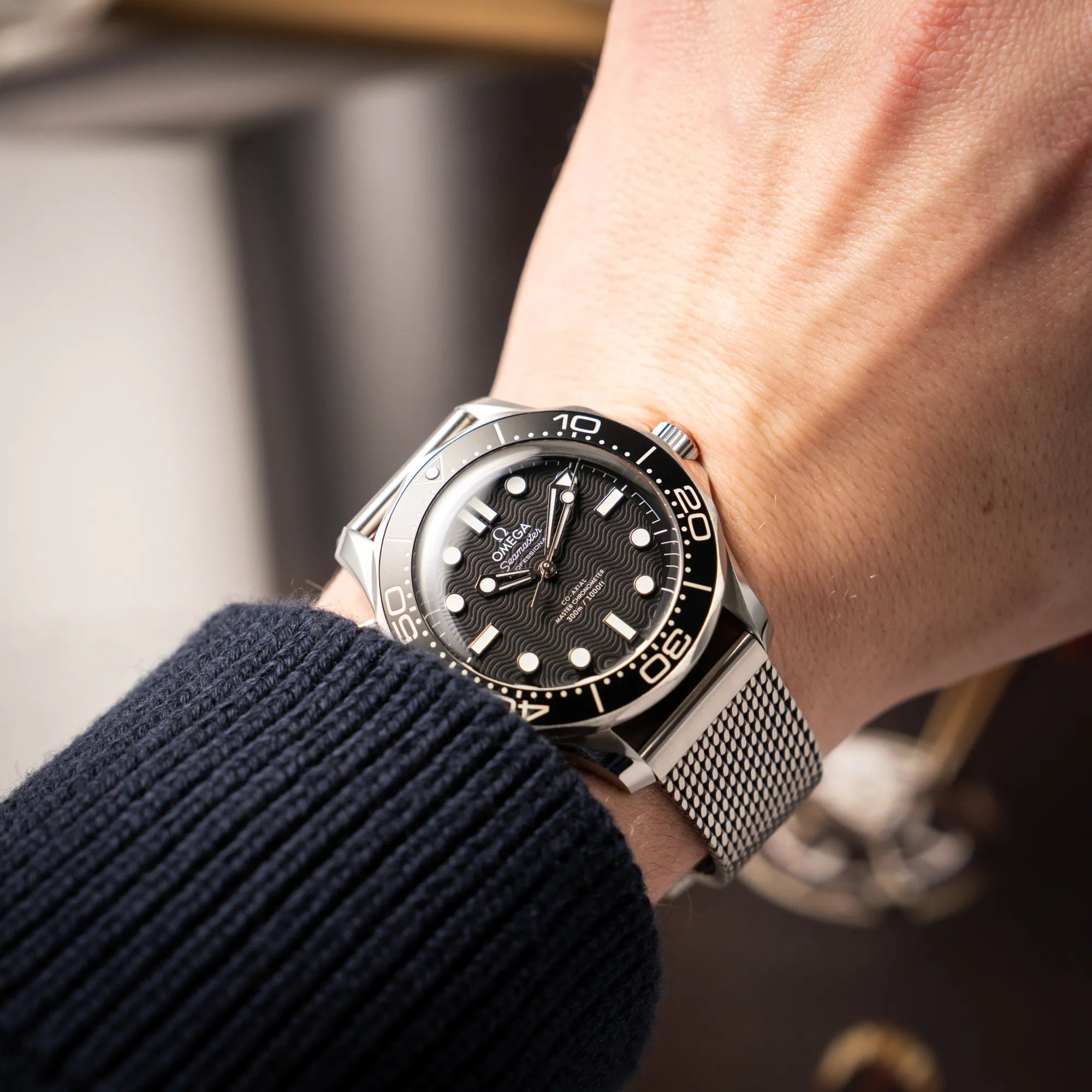 Mannerhandgelek mit der Omega Seamaster 300M Diver 210.30.42.20.01.010 mit dems schwarzen Zifferblatt im Wellen-Design am Milanese-Edelstahl-Armband