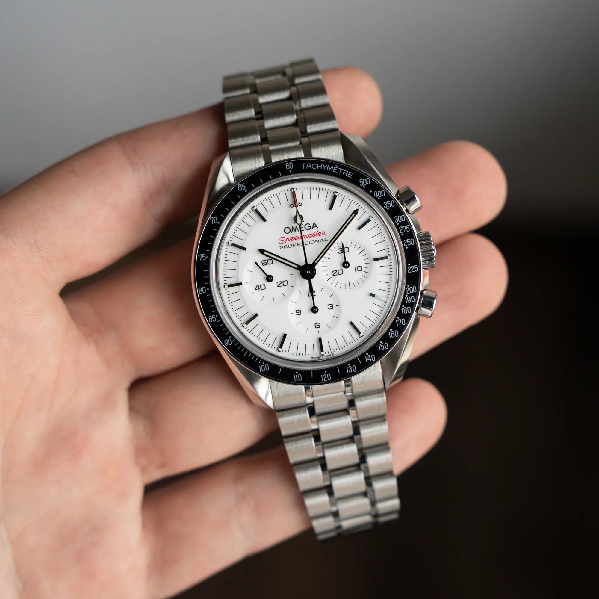 Mann hält die Speedmaster Professional Moonwatch von Omega mit dem neuen weißen Zifferblatt in seiner Hand