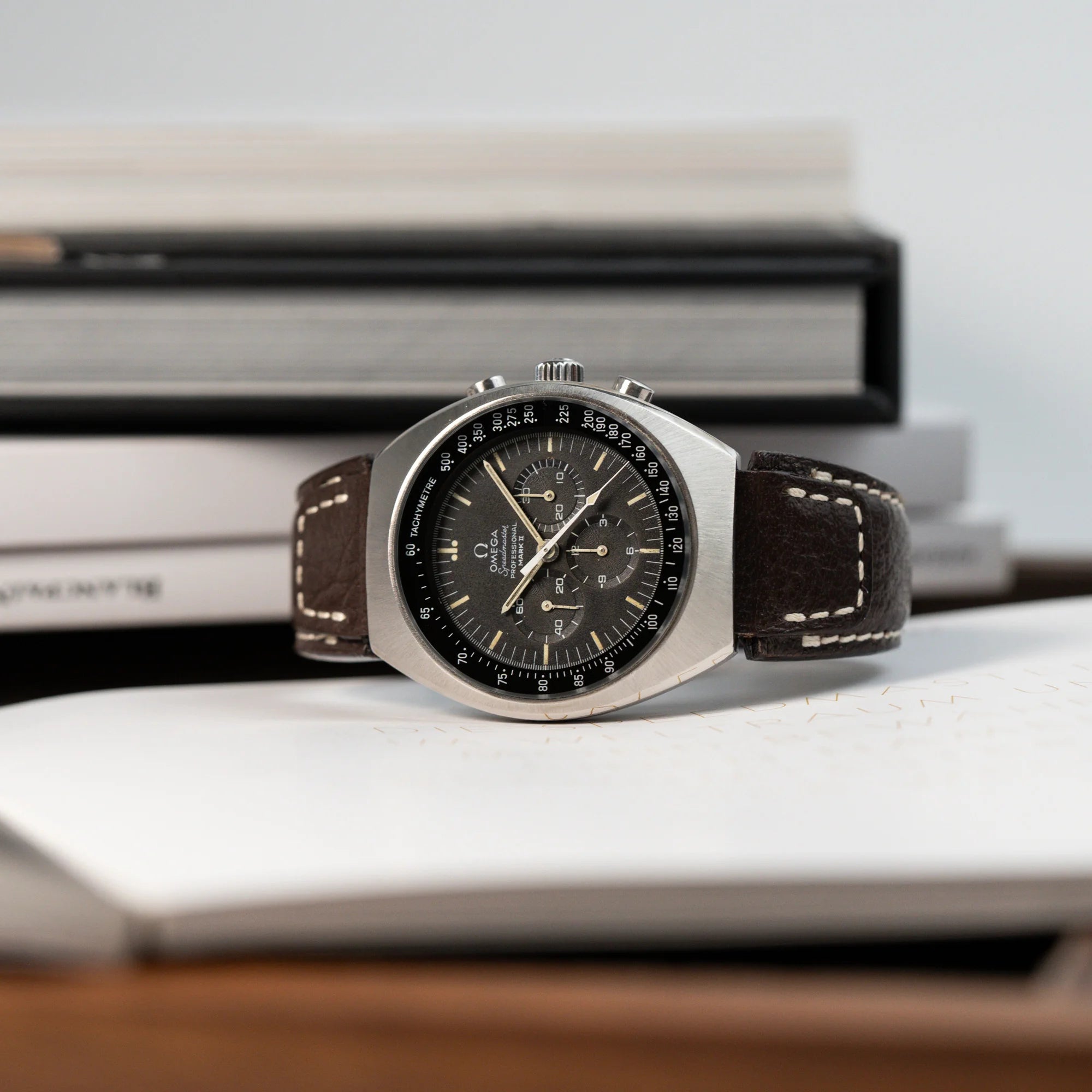 Produktfotografie der liegenden Omega Speedmaster Moonwatch Mark 2 an einem braunen Lederarmband