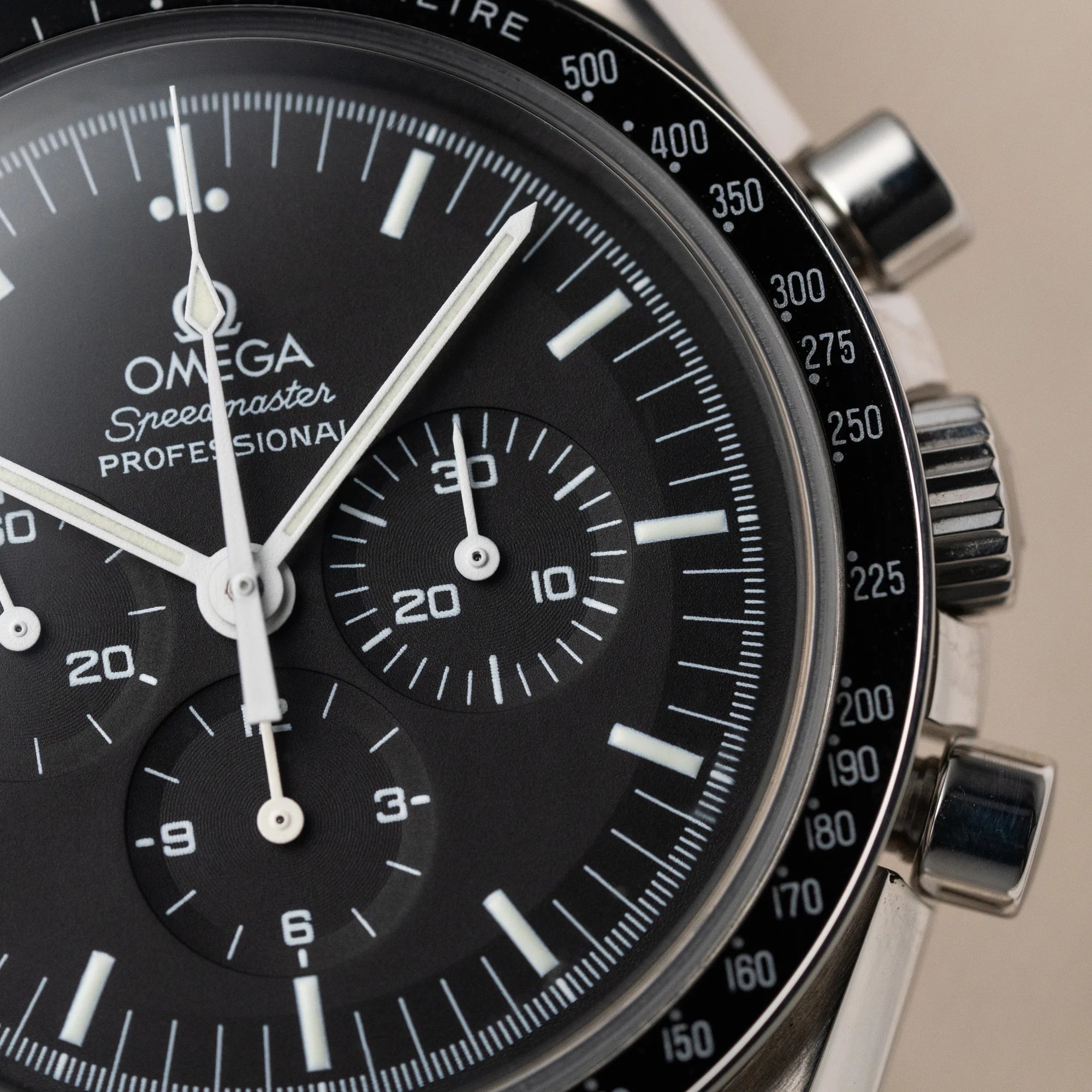 Detailaufnahme der Omega Speedmaster Moonwatch Professional am schwarzen Lederband mit Fokus auf dem Zifferblatt und der Lünette