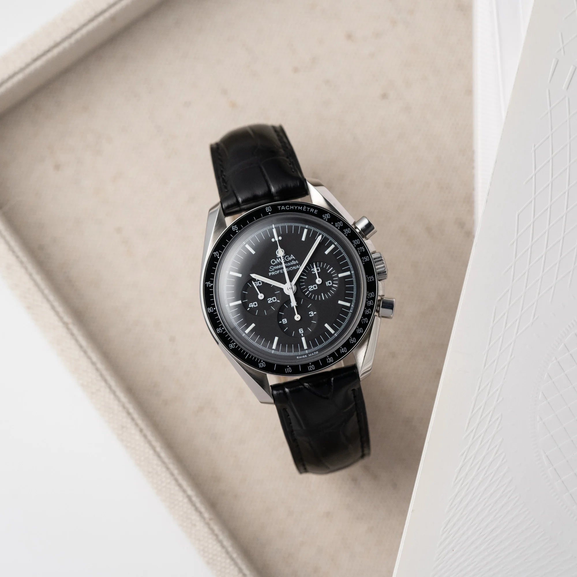 Produktfotografie der Omega Speedmaster Moonwatch Professional am schwarzen Lederband von oben herab