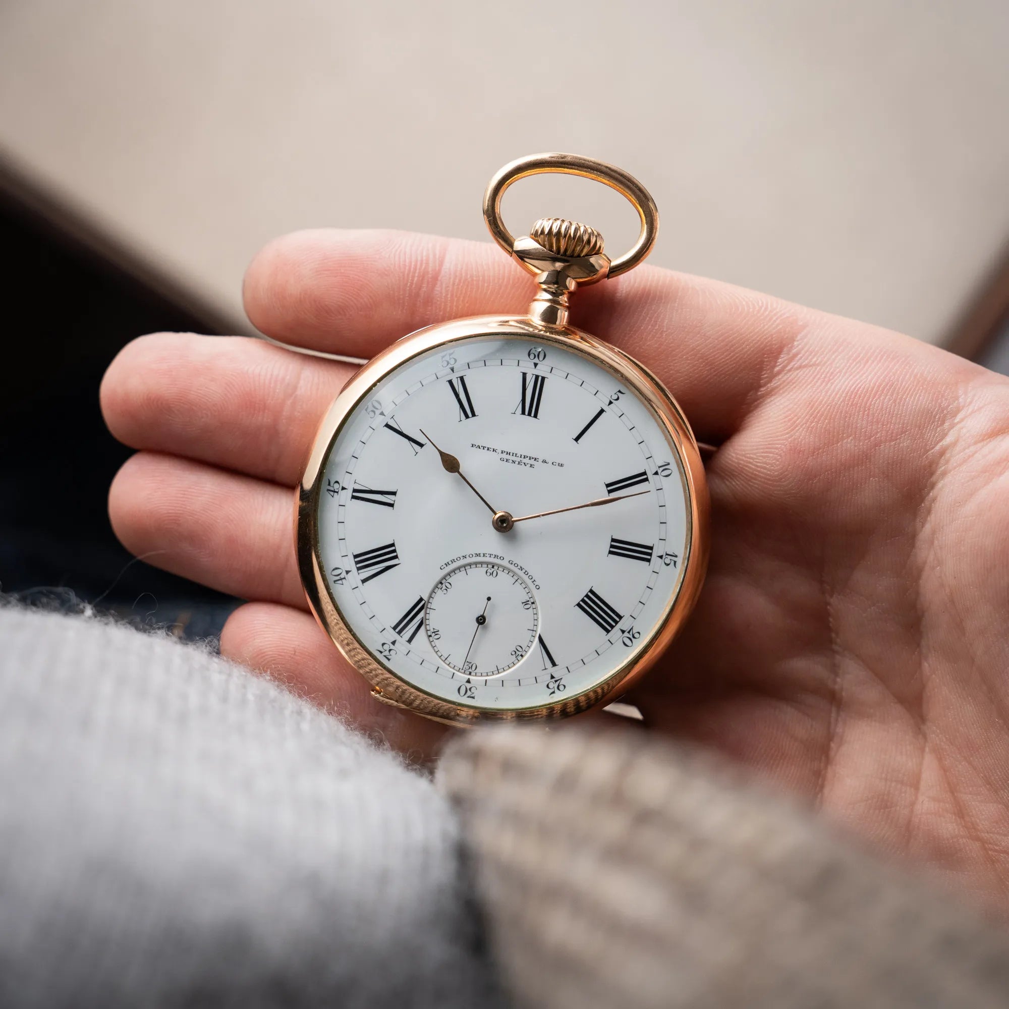 Mann hält die Patek Philippe Gondolo Taschenuhr aus 18k Gelbgold mit weißem Zifferblatt und römischen Indizes in seiner Hand