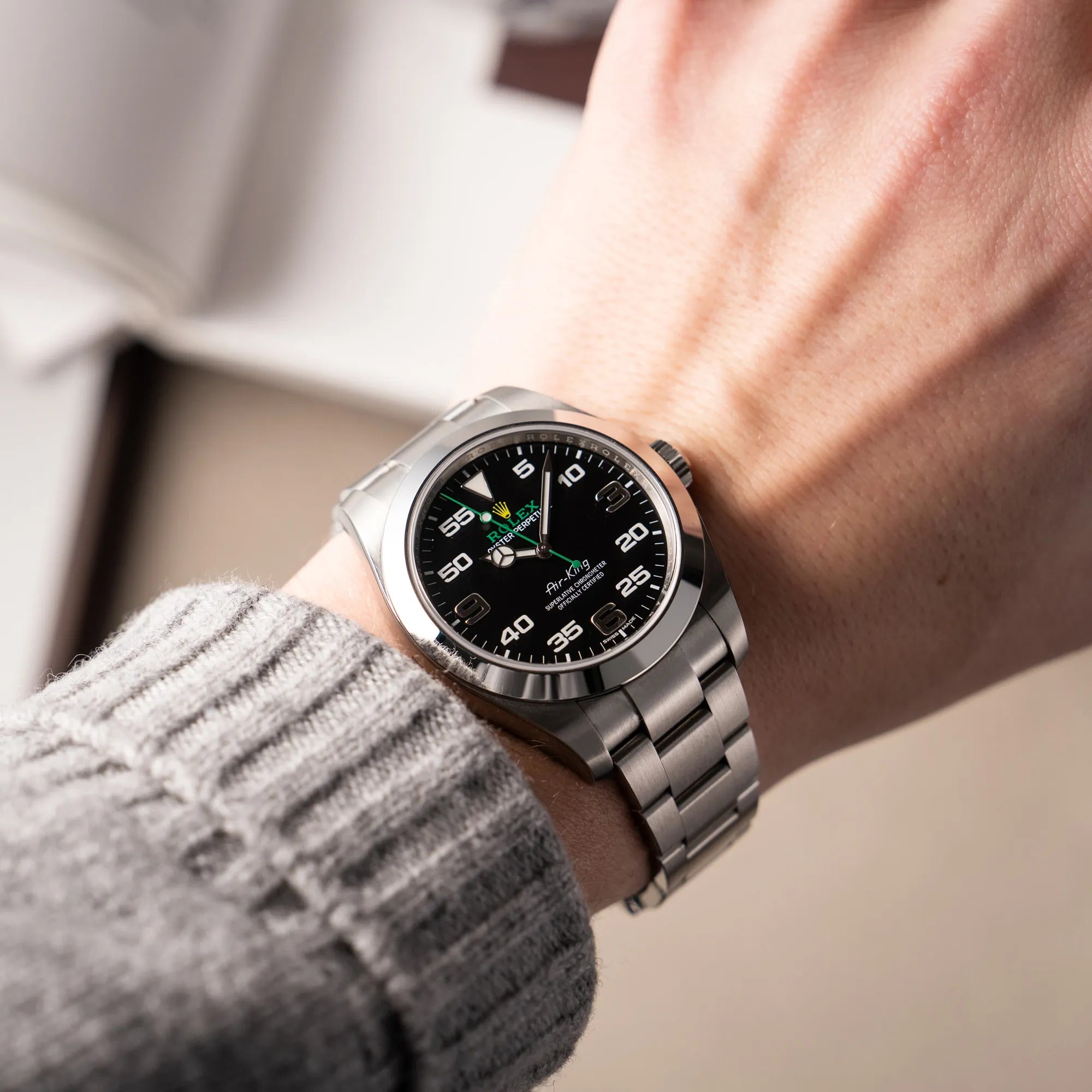 Mann trägt die Rolex Oyster Perpetual Air King 116900 mit 40mm Gehäuse und dem klassischen schwarzen Zifferblatt mit grünem Sekundenzeiger für einen Wristshot an seinem Handgelenk