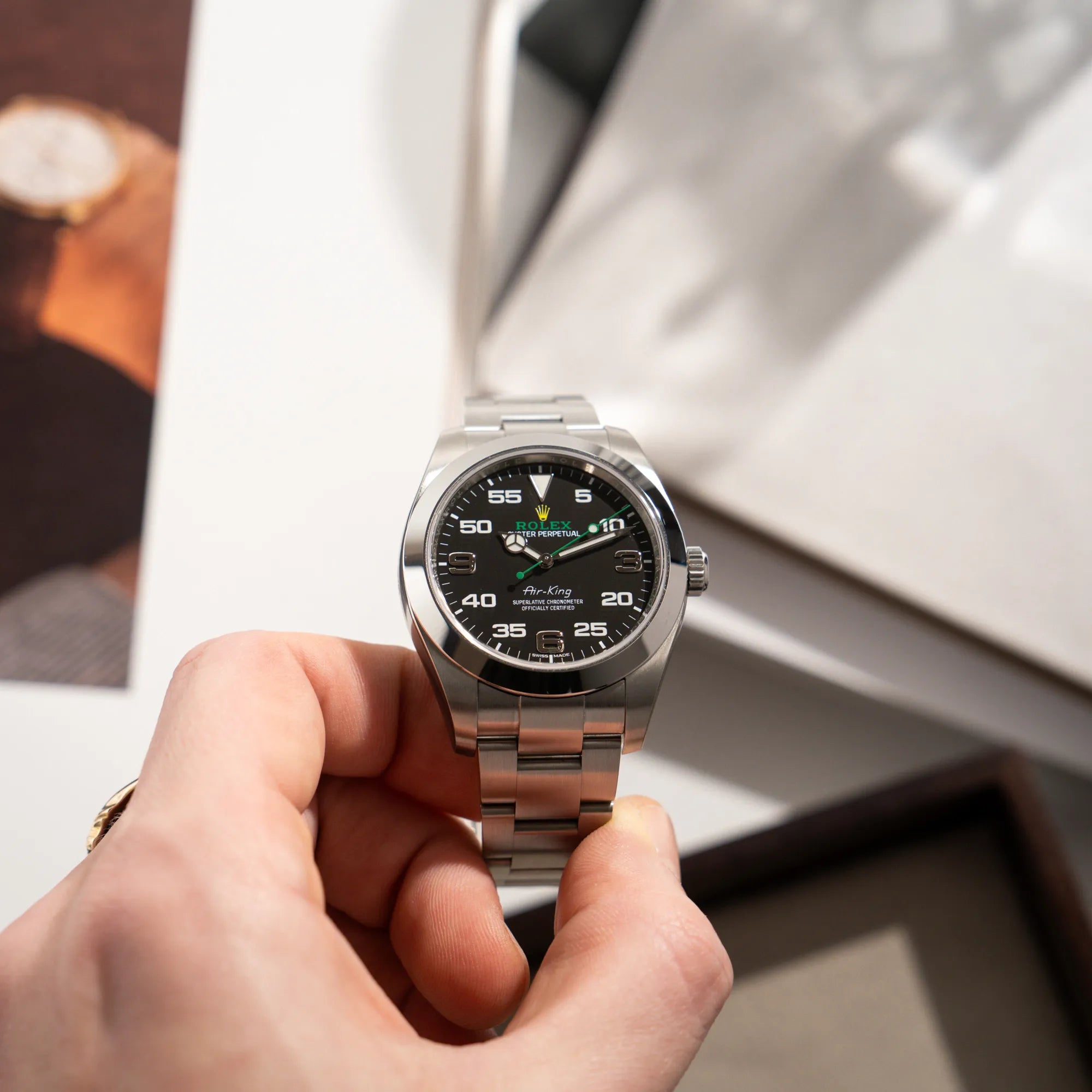 Mann präsentiert die Rolex Oyster Perpetual Air King 116900 mit 40mm Gehäuse und dem klassischen schwarzen Zifferblatt mit grünem Sekundenzeiger
