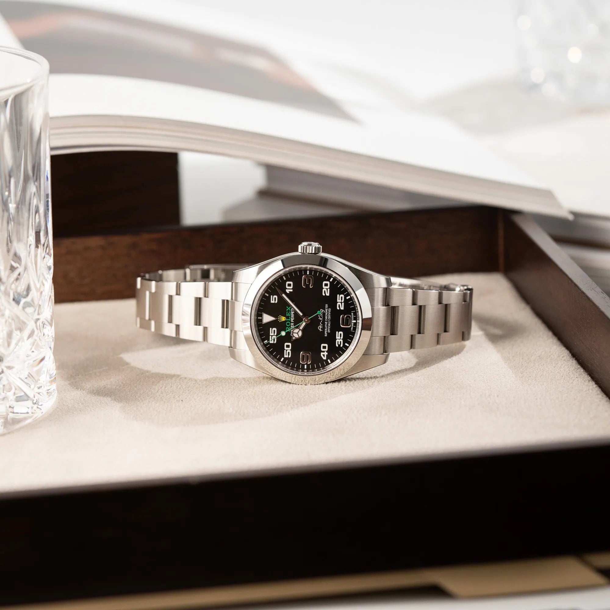 Produktfotografie der seitliche liegenden Rolex Oyster Perpetual Air King 116900 mit 40mm Gehäuse und dem klassischen schwarzen Zifferblatt mit grünem Sekundenzeiger