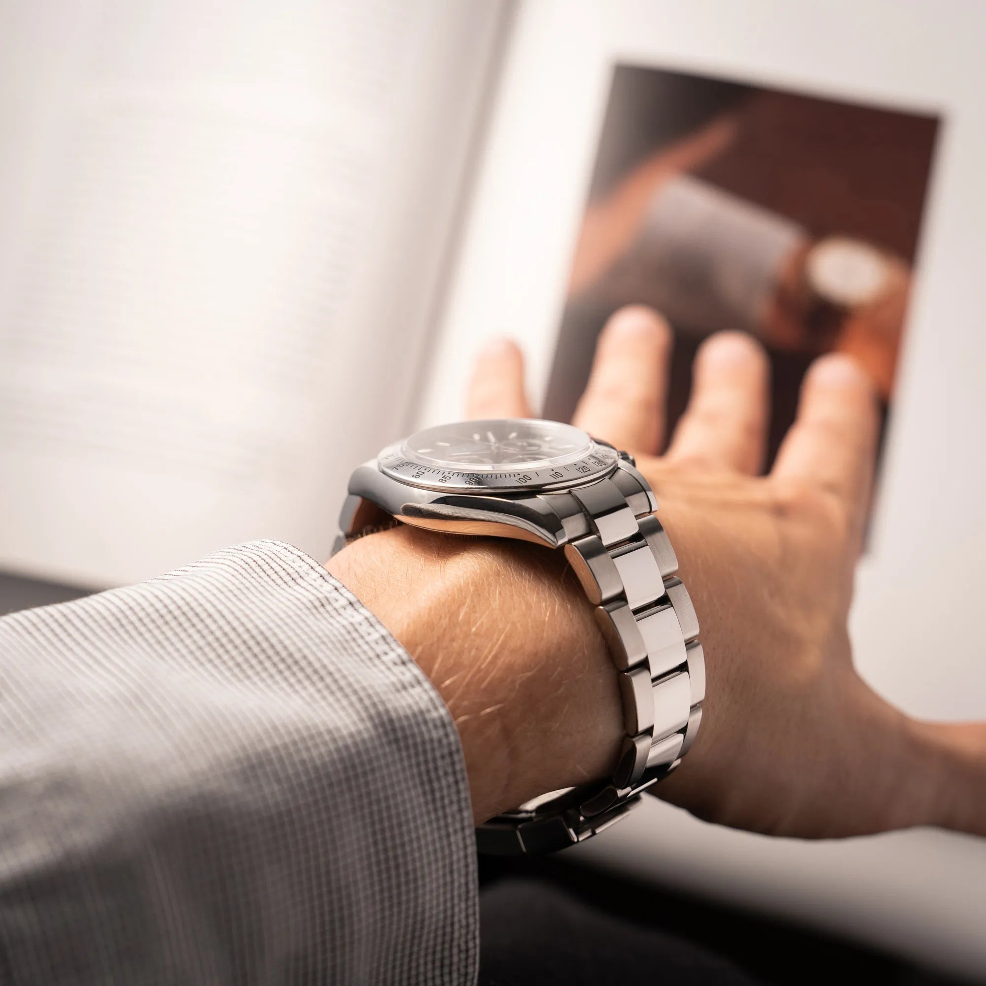 Mann präsentiert die Rolex Cosmograph Daytona 116520 mit schwarzem Zifferblatt und der klassischen Edelstahl-Lünette vor Umstellung auf die Keramik-Lünette an seinem Handgelenk