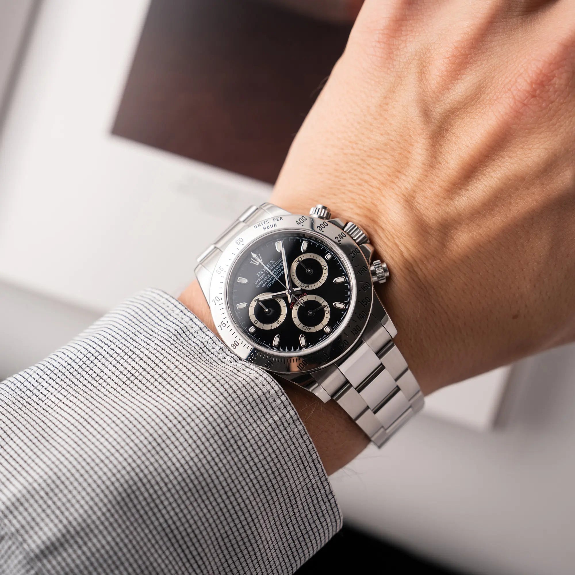 Mann trägt die Rolex Cosmograph Daytona 116520 mit schwarzem Zifferblatt und der klassischen Edelstahl-Lünette vor Umstellung auf die Keramik-Lünette für einen Wirstshot an seinem Handgelenk