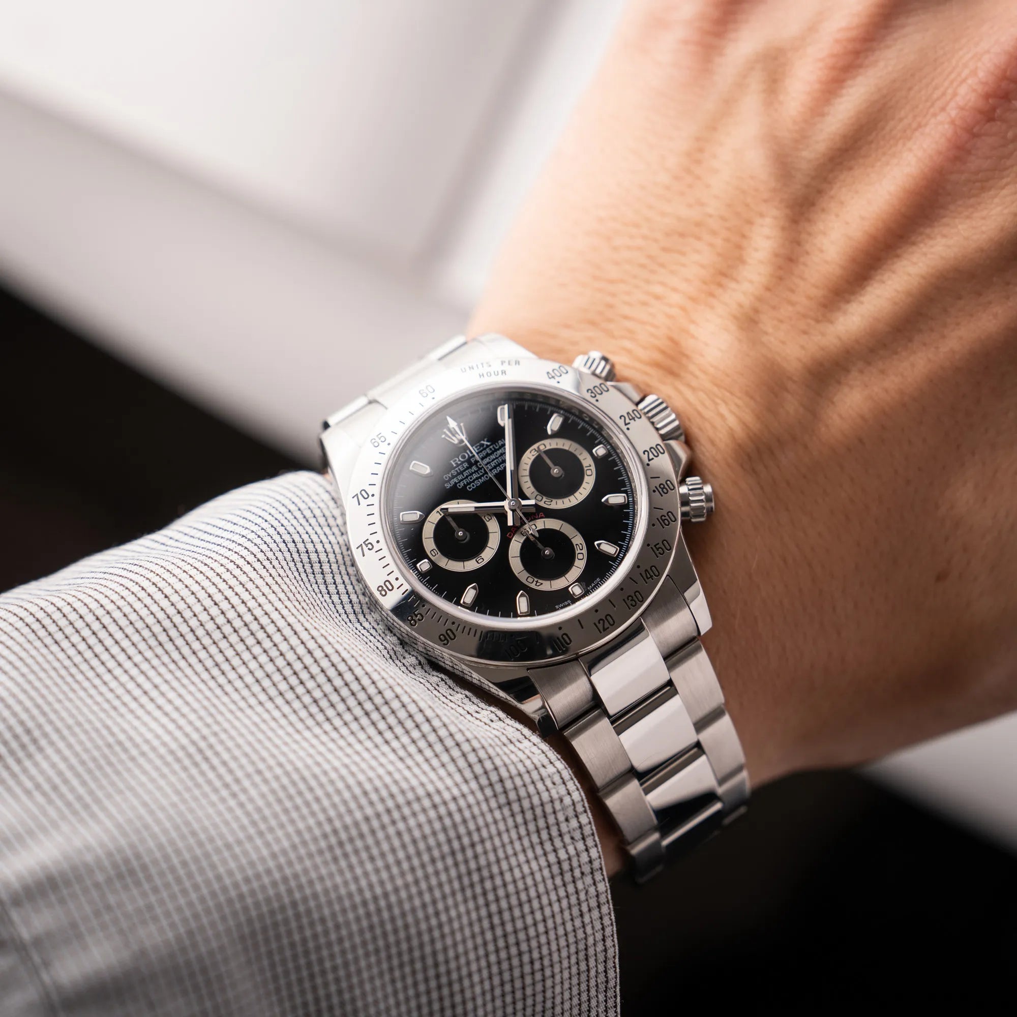 Mann präsentiert die Rolex Cosmograph Daytona 116520 mit schwarzem Zifferblatt und der klassischen Edelstahl-Lünette vor Umstellung auf die Keramik-Lünette an seinem Handgelenk als Wristshot