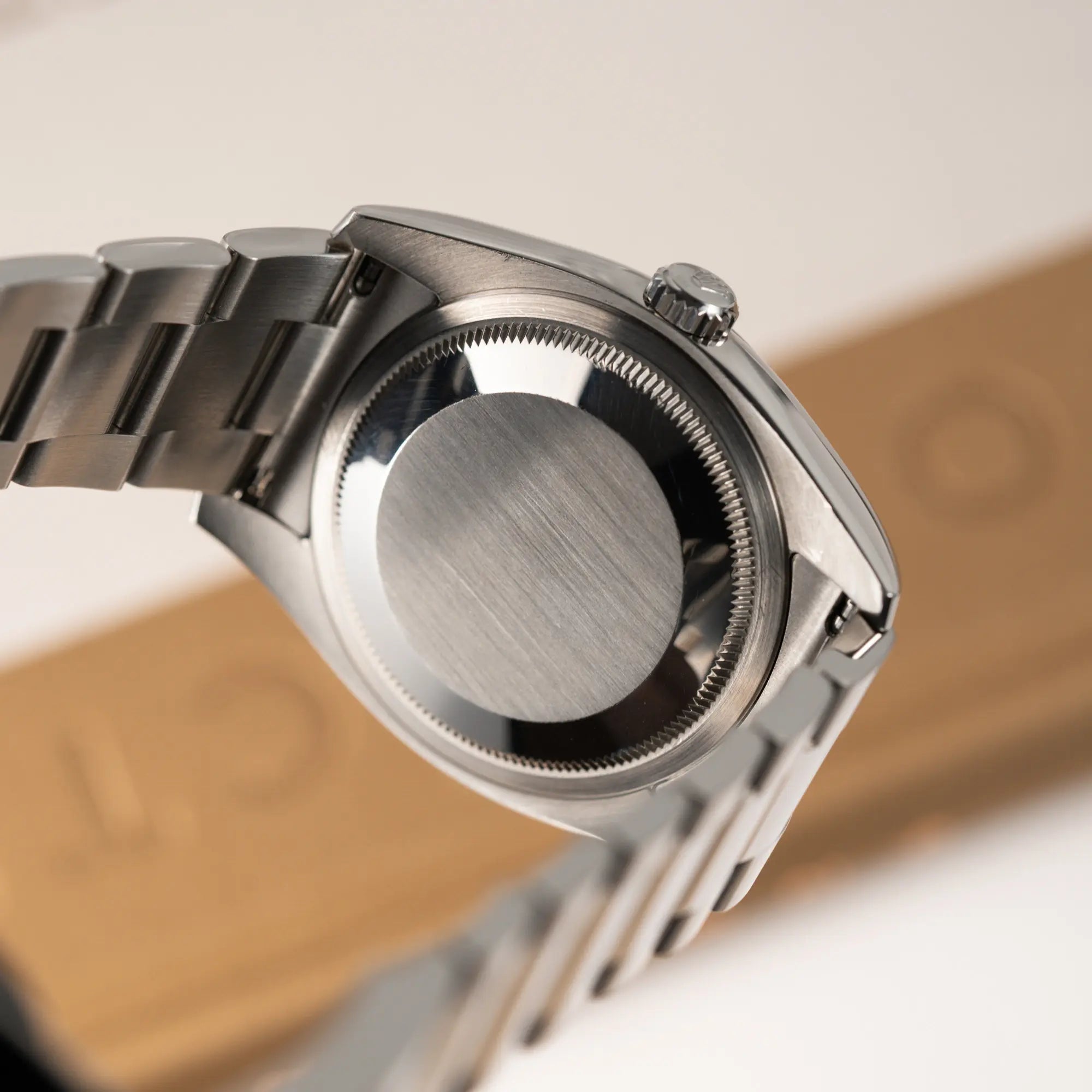 Produktfotografie der Rolex Datejust 36 der Referenz 116234 mit geriffelter Lünette und blauem Sonnenschliff-Zifferblatt zeigt den verschraubten Gehäuseboden aus Stahl und dessen Zustand