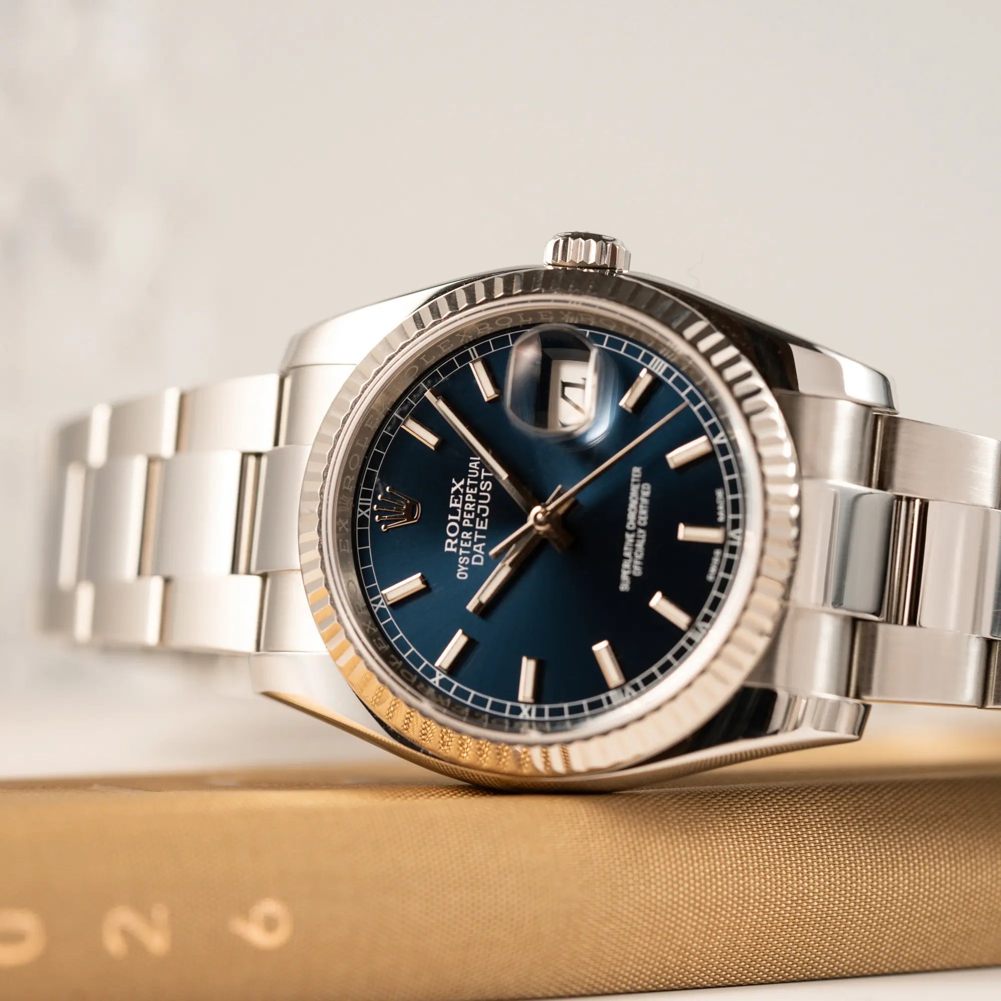 Detailaufnahme der seitlich liegenden Rolex Datejust 36 der Referenz 116234 mit geriffelter Lünette und blauem Sonnenschliff-Zifferblatt