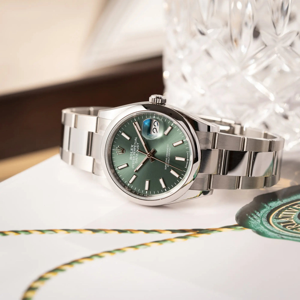 mit Stickern teil-verklebte Rolex Datejust 36 der Referenz 126200 mit glatter Lünette am Oyster-Stahlband mit dem Mint-Green-Zifferblatt  liegt auf einem Rolex-Magazin