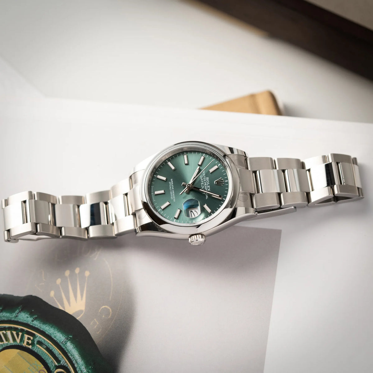 mit Stickern teil-verklebte Rolex Datejust 36 der Referenz 126200 mit glatter Lünette am Oyster-Stahlband mit dem Mint-Green-Zifferblatt liegt flach auf einem Rolex-Magazin
