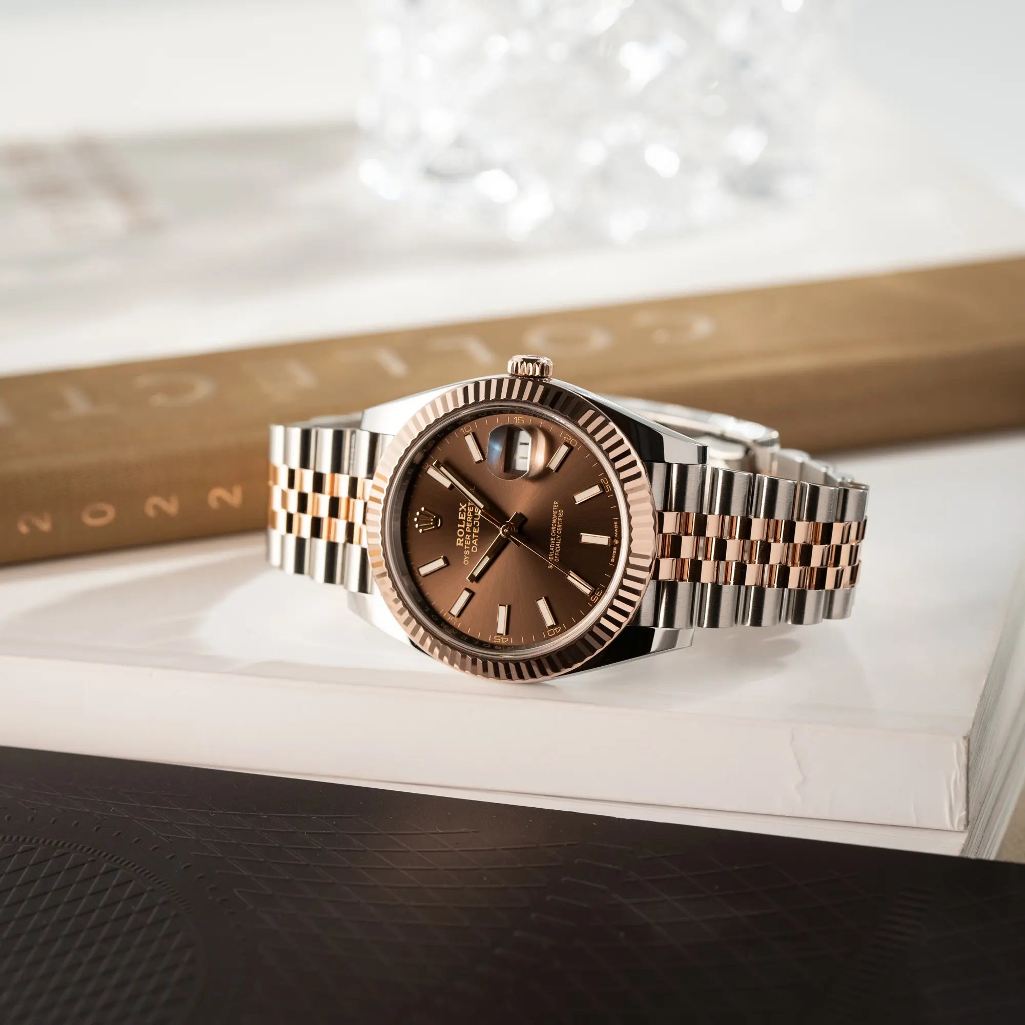 Produktfotografie der seitlich auf dem Uhrengehäuse liegenden bicolor Rolex Datejust 41 der Referenz 126331 Chocolate in Stahl-Roségold mit einem zum Roségold passenden braunen Zifferblatt am zugehörigen Jubilee-Armband