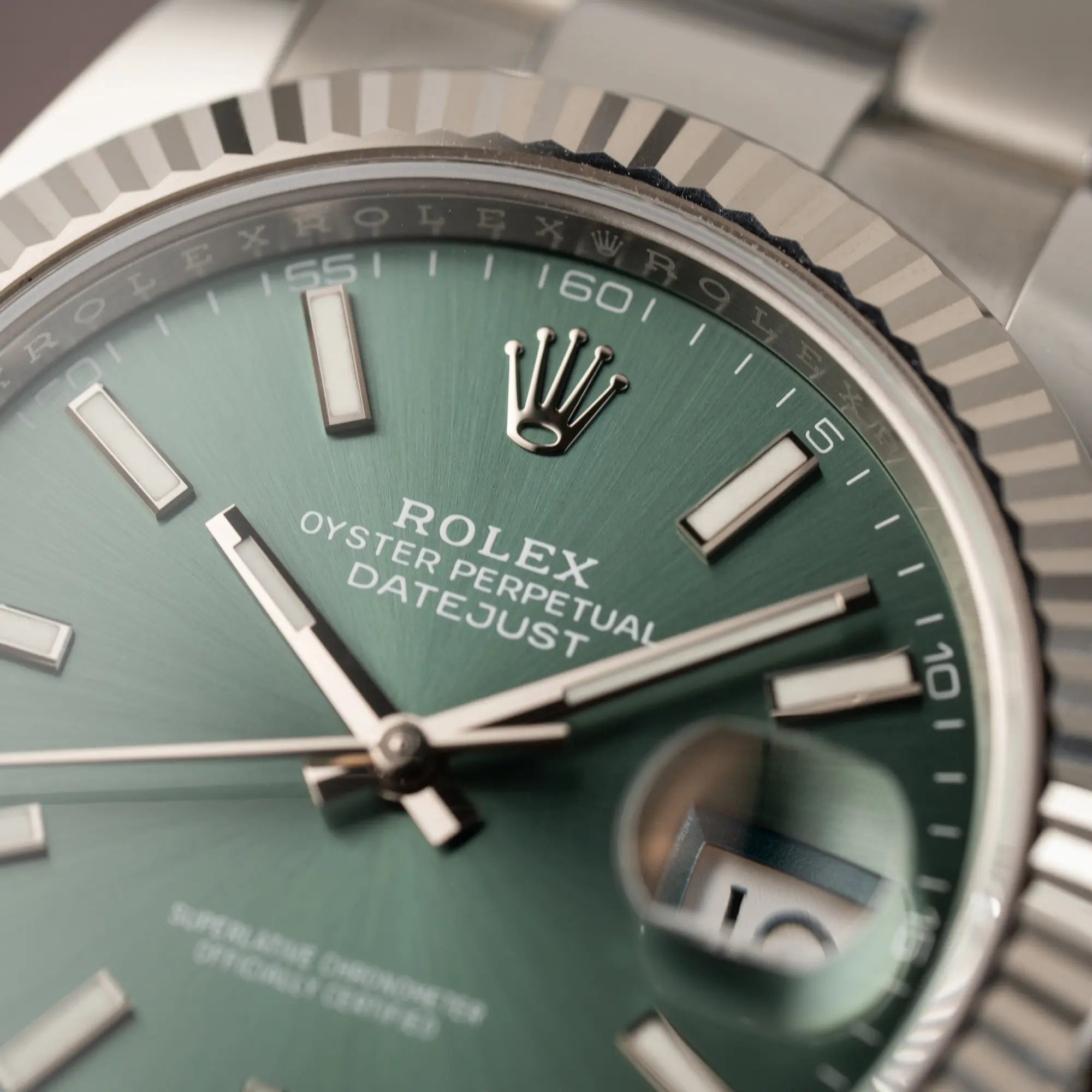 Makroaufnahme der Rolex Krone bei 12 Uhr auf dem Zifferblatt der Rolex Datejust 41 der Referenz 126334 mit dem grünem Zifferblatt am Oyster-Stahlband
