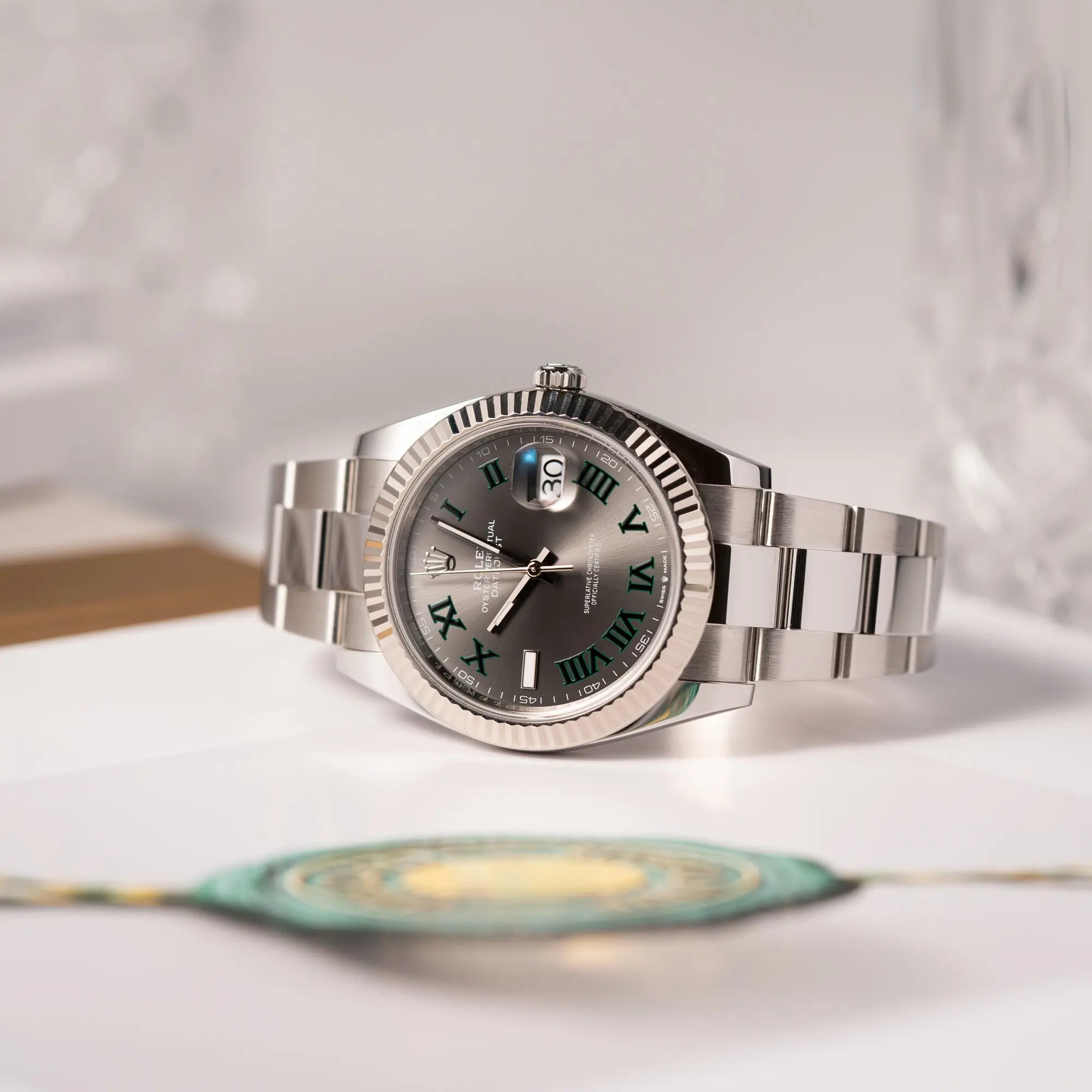 Produkfotografie der Rolex Datejust 41 der Referenz 126334 mit geriffelter Weißgold-Lünette und Oyster-Stahlband mit dem grauen Wimbledon-Zifferblatt mit schwarz-grünen Indizes