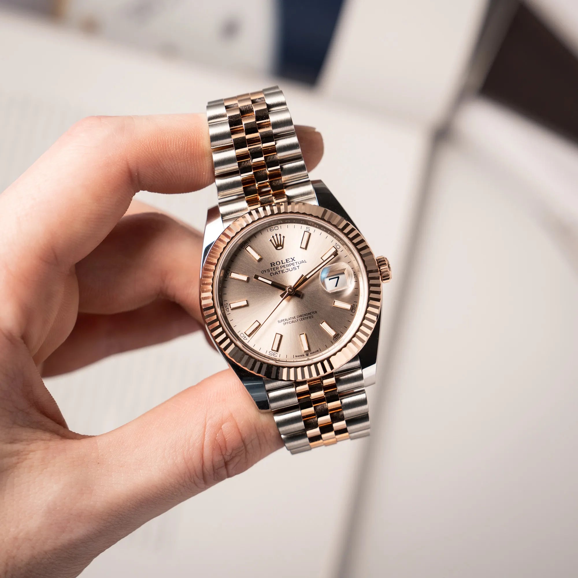 Mann hält die Rolex Datejust 41 in Stahl-Roségold mit am passenden Jubilee-Armband mit dem pink-lachsfarbenen "Sundust" Zifferblatt in seiner Hand und präsentiert die Uhr in die Kamera