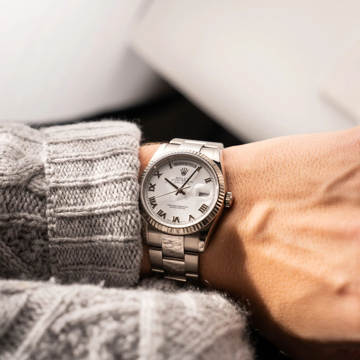 Mann trägt die Rolex Day-Date 36 Armbanduhr in Weißgold der Referenz 118239 mit weißem Zifferblatt mit römischen Indizes am Oyster-Weißgold-Armband an seinem Handgelenk und präsentiert die Uhr in die Kamera