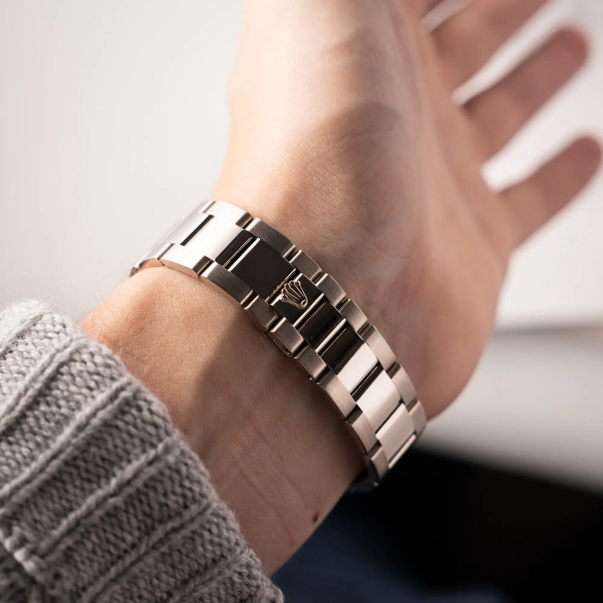 Mann trägt die Rolex Day-Date 36 Armbanduhr in Weißgold der Referenz 118239 mit weißem Zifferblatt mit römischen Indizes am Oyster-Weißgold-Armband an seinem Handgelenk und präsentiert die verdeckte Faltschliesse in die Kamera