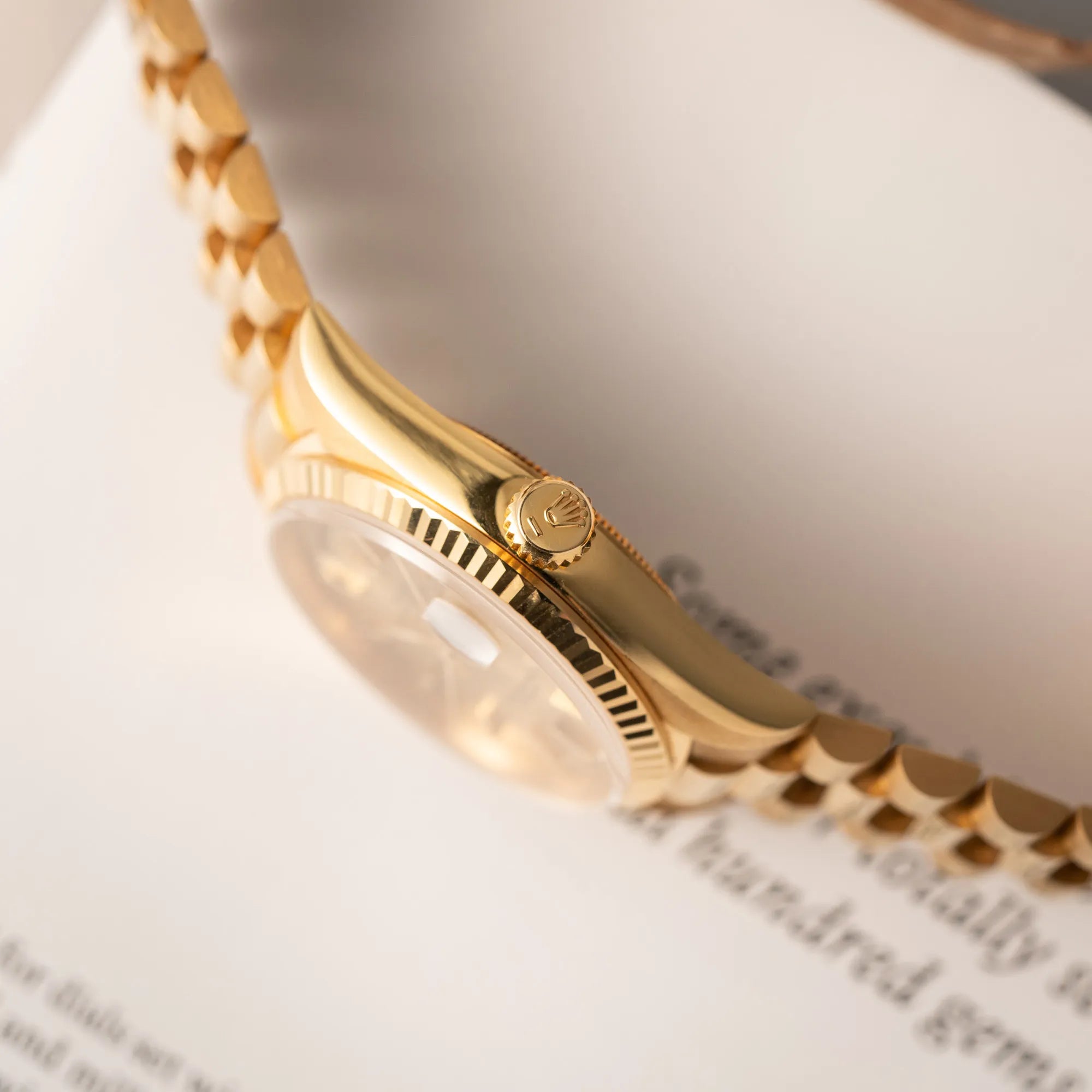 Produktfotografie zeigt die seitliche Gehäuseflanke mit Blick auf die Aufzugskrone der Rolex Day-Date 36 der Referenz 18238 in Gelbgold mit champagnerfarbenem Stick-Dial