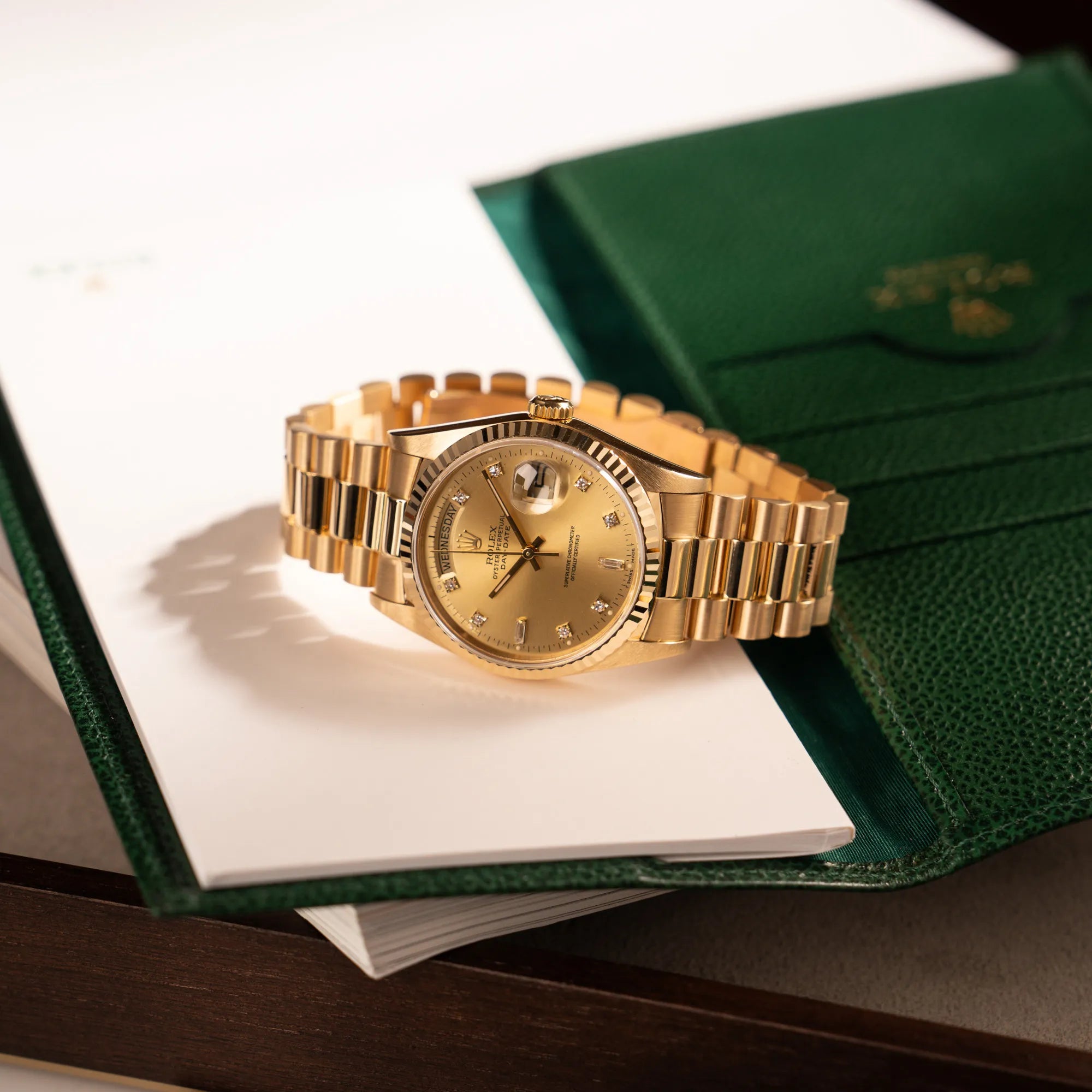 Produktfotografie der Rolex Day-Date 36 in Gelbgold mit der Referenz 18238 und Champagne-Diamant-Zifferblatt zusammen mit Rolex-Schreibblock