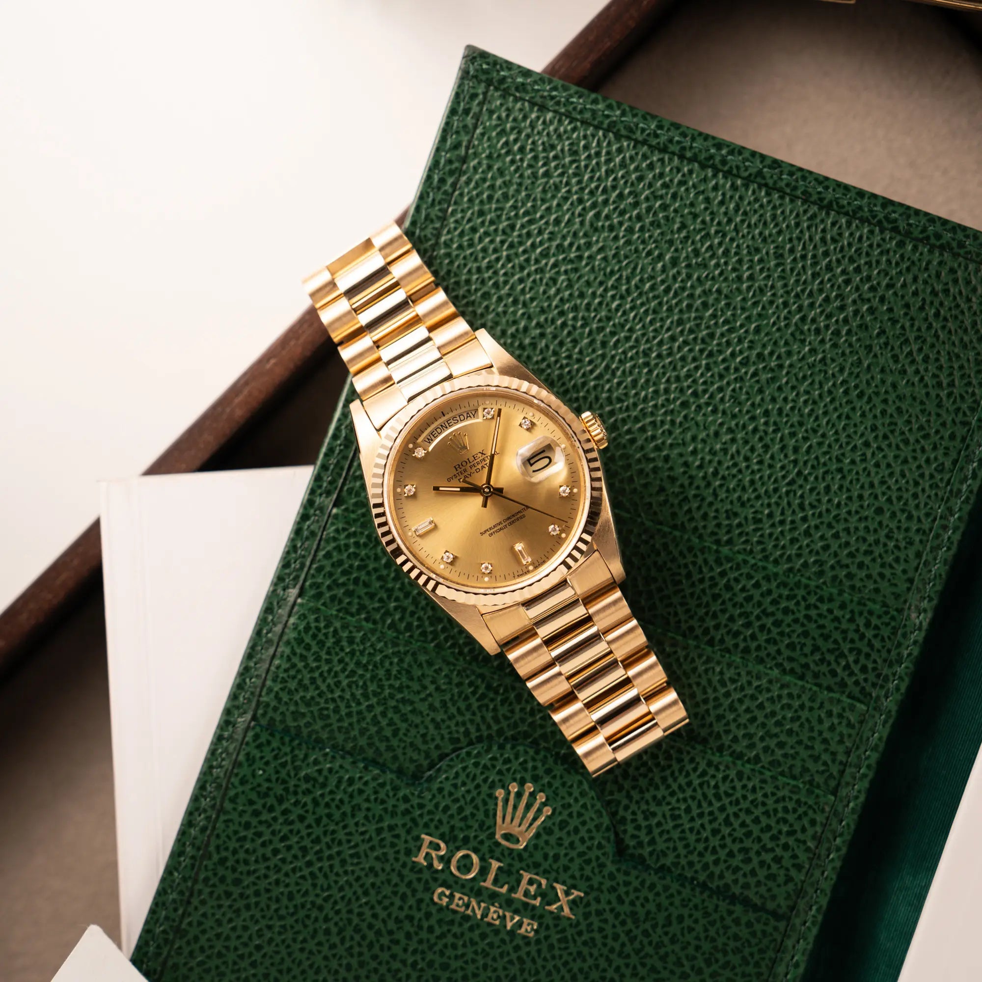 Produktfoto der Rolex Day-Date 36 in Gelbgold mit der Referenz 18238 und Champagne-Diamant-Zifferblatt zusammen mit einem grünem Rolex-Kartenetui