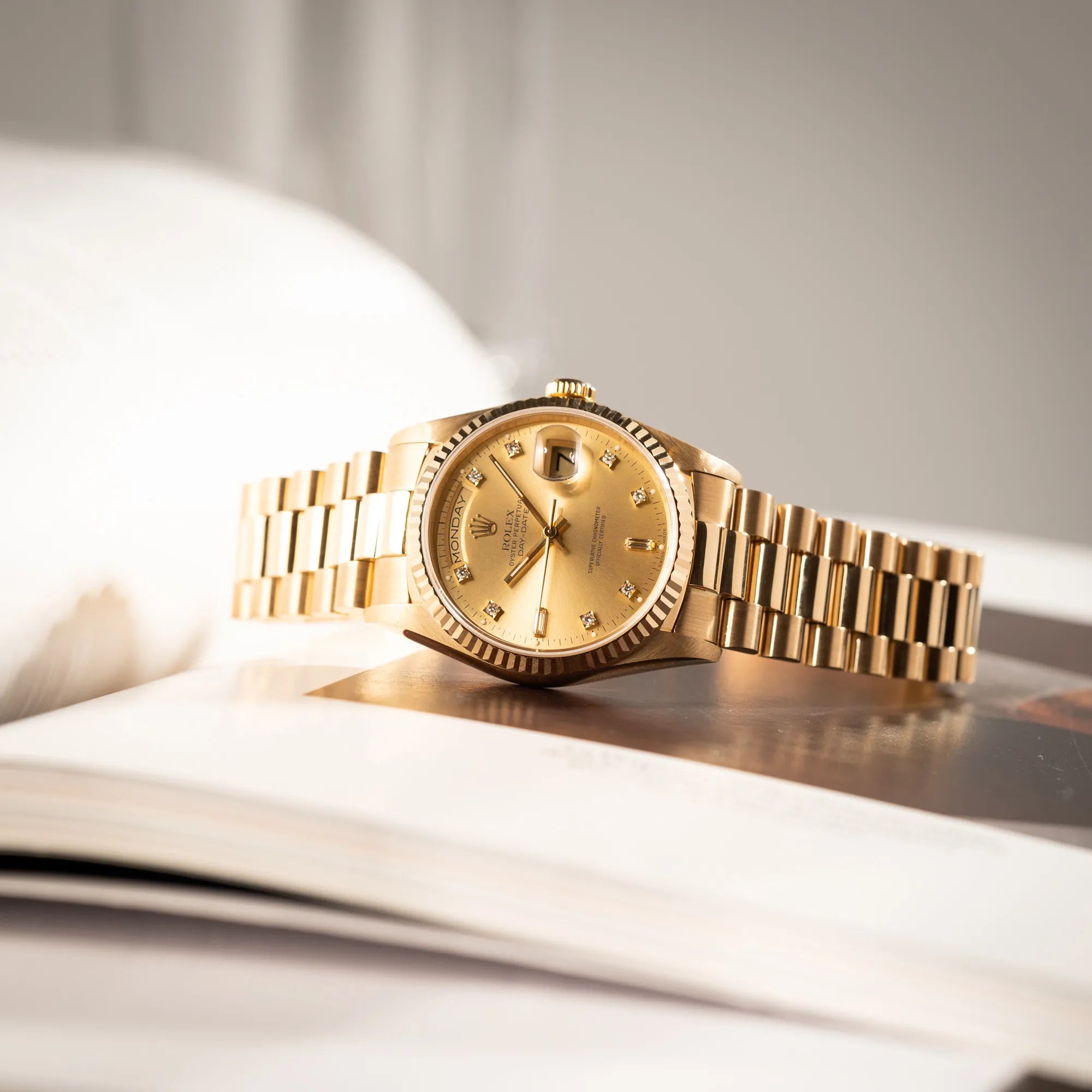 Produktfotografie der seitlich auf dem Uhrengehäuse liegenden Rolex Day-Date 36 in Gelbgold der Referenz 18238 aus 1991 mit Champagner-Diamant-Zifferblatt und englischsprachiger Tagesanzeige
