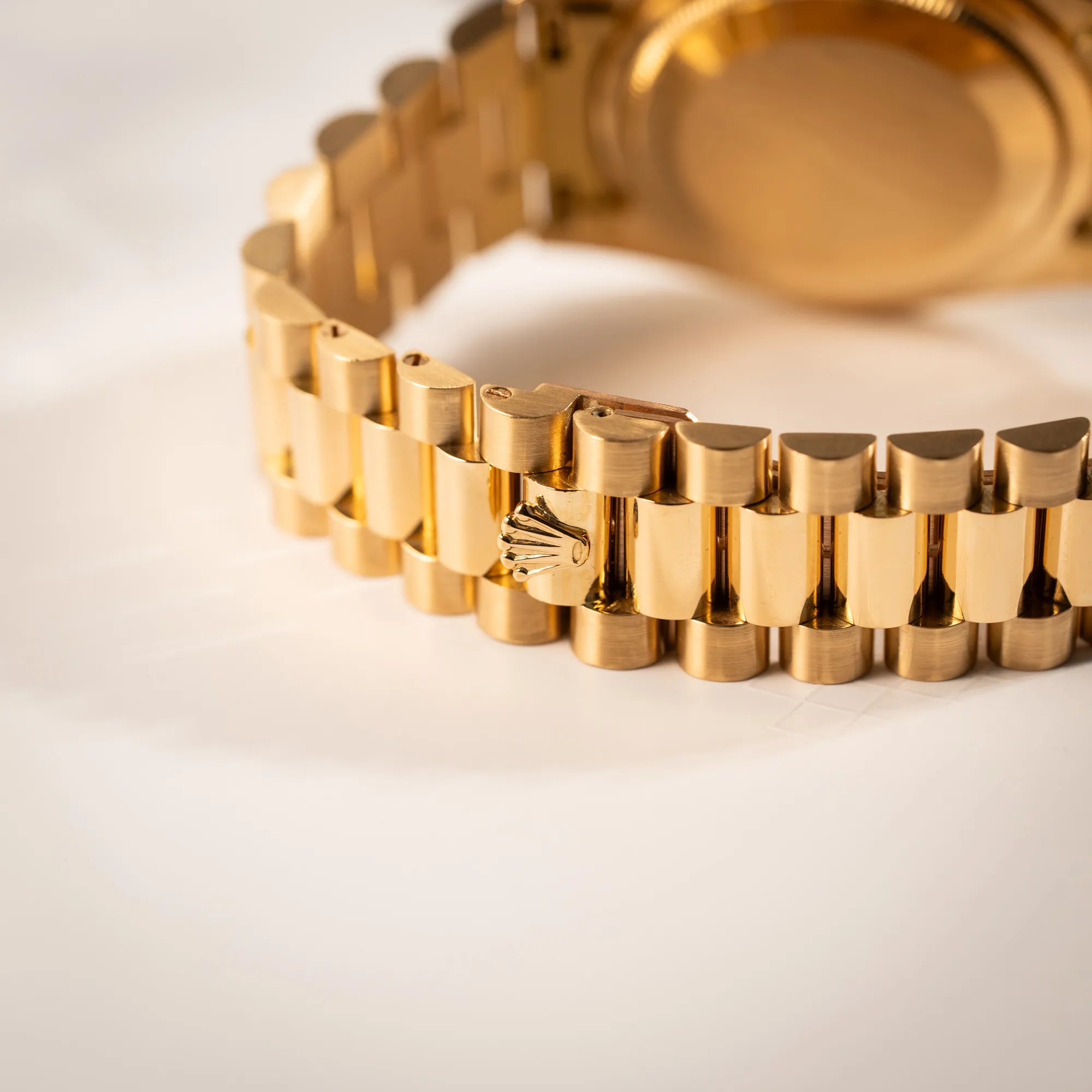 Detailaufnahme der Rolex-Krone auf der Schliesse des President-Armbands von der Rolex Day-Date 36 in Gelbgold der Referenz 18238 aus 1991 mit Champagner-Diamant-Zifferblatt und englischsprachiger Tagesanzeige