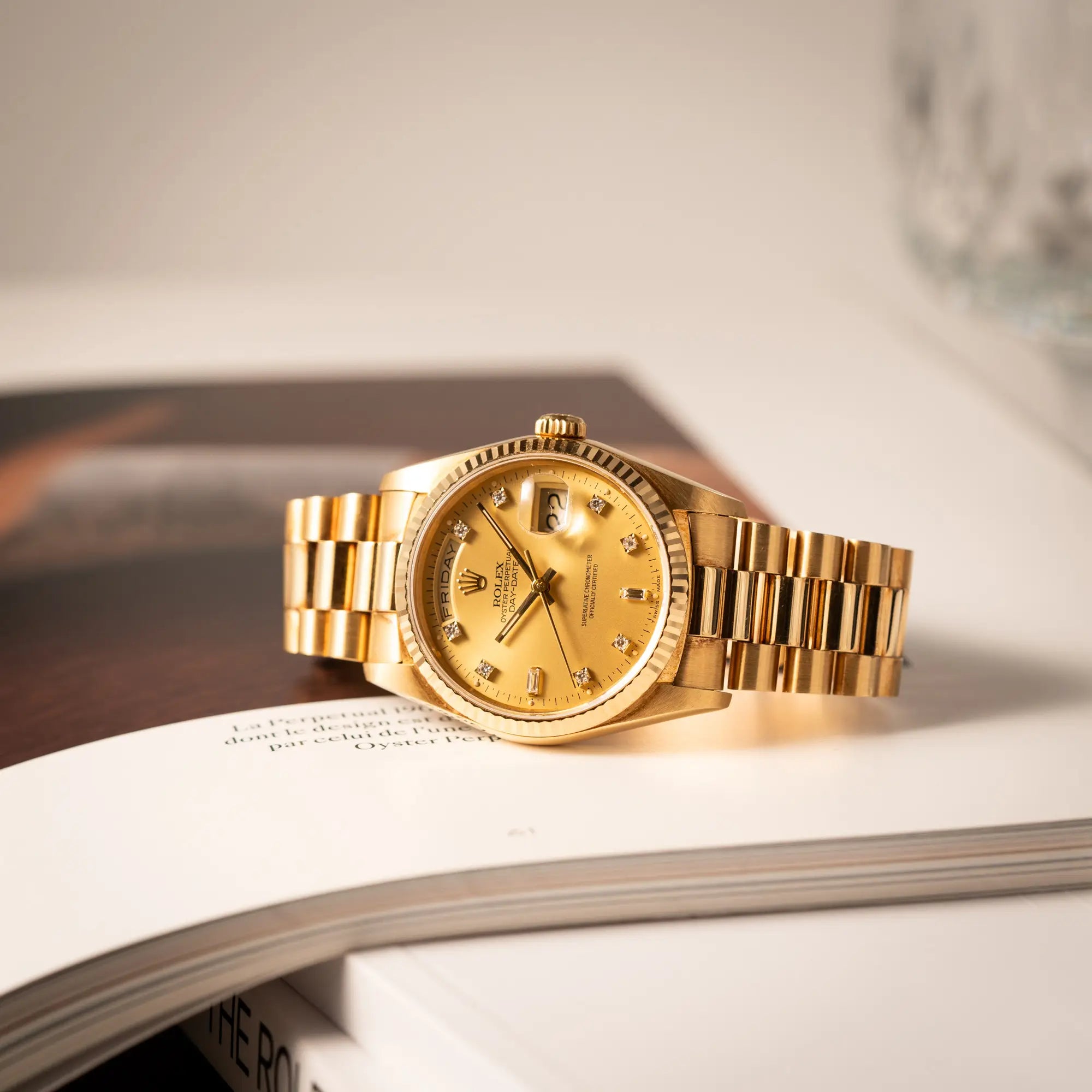 Rolex Day-Date 36 der Referenz 18238 mit champagnerfarbenem Diamant-Zifferblatt liegt auf der seitlichen Gehäuseflanke