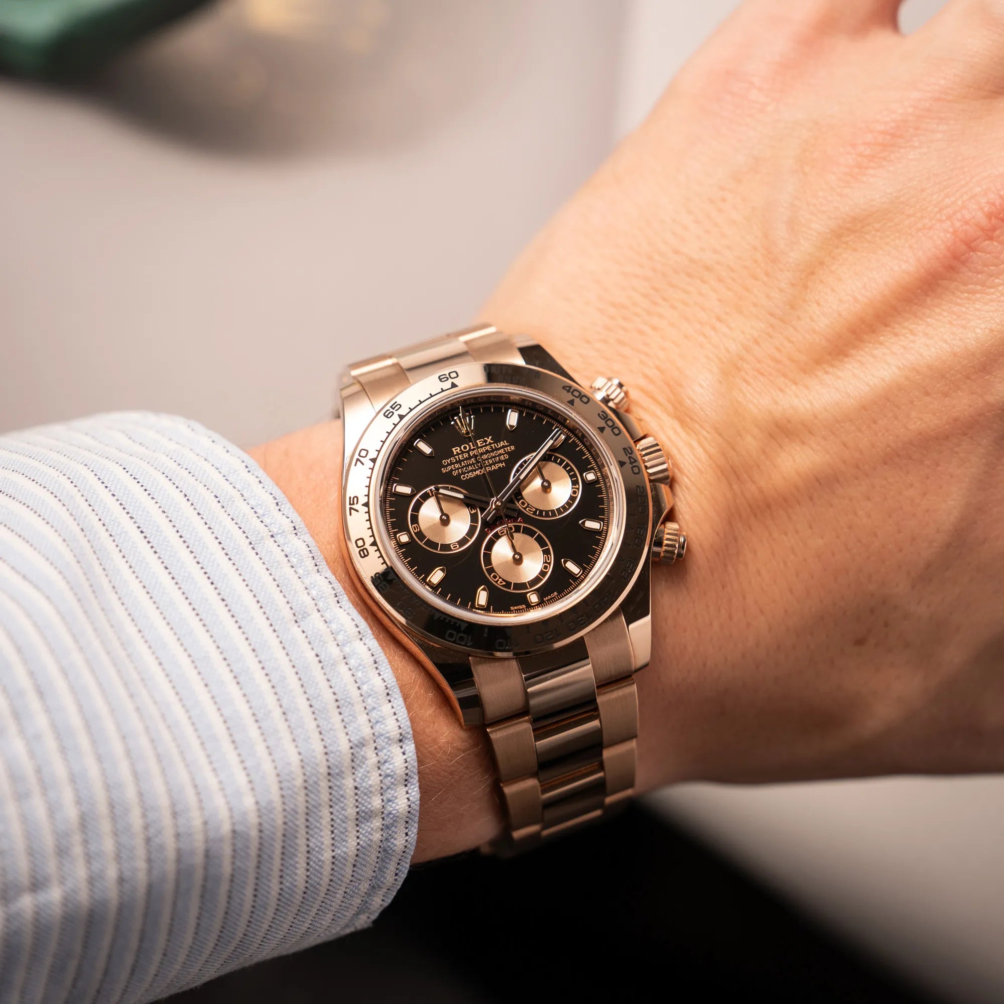 Mann trägt die Rolex Daytona Chronograph-Armbanduhr der Referenz 116505 in Everrose-Roségold mit schwarzem Zifferblatt am Oyster-Roségold-Band an seinem Handgelenk