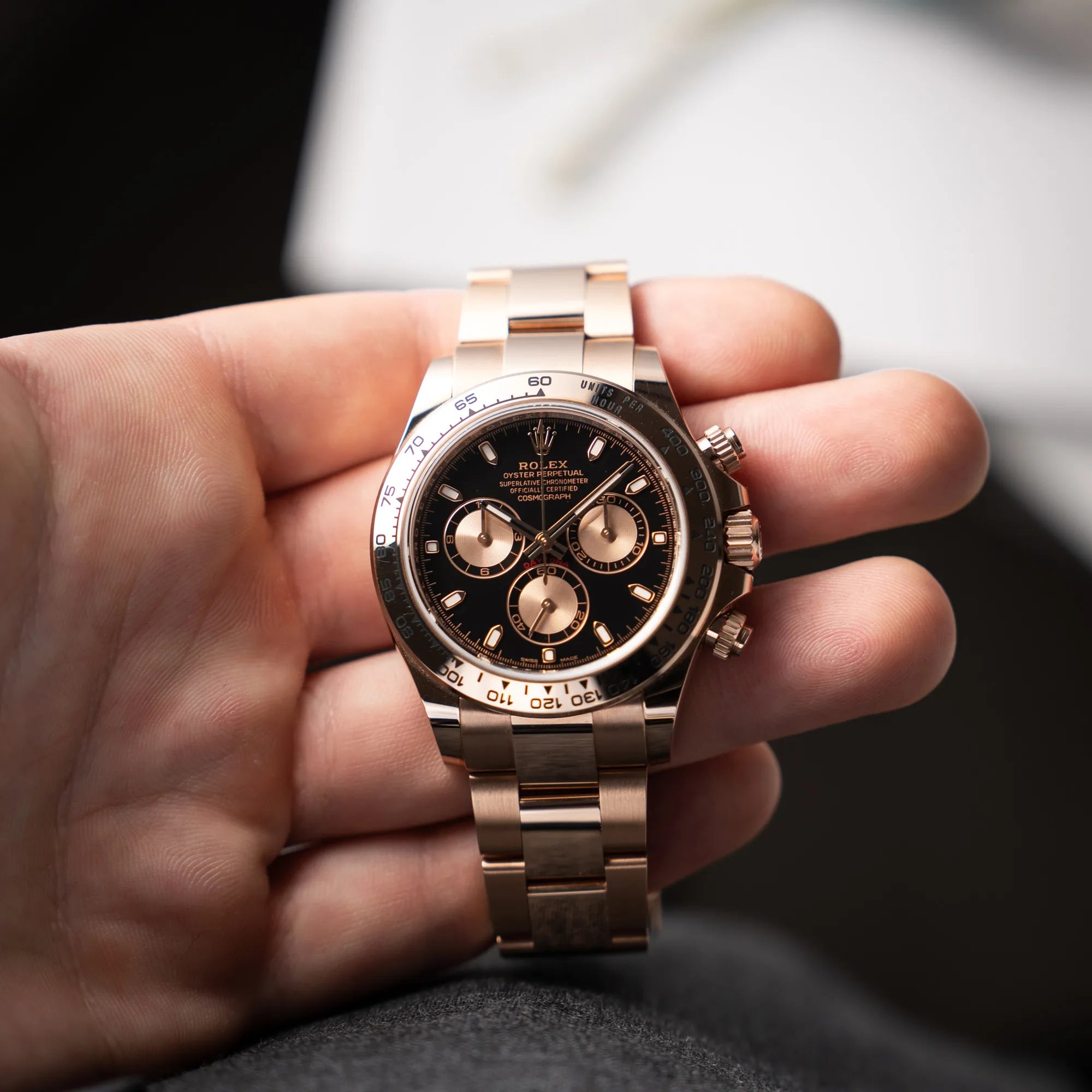 Mann hält die Rolex Daytona Chronograph-Armbanduhr der Referenz 116505 in Everrose-Roségold mit schwarzem Zifferblatt am Oyster-Roségold-Band in seiner Hand und präsentiert die Uhr in die Kamera