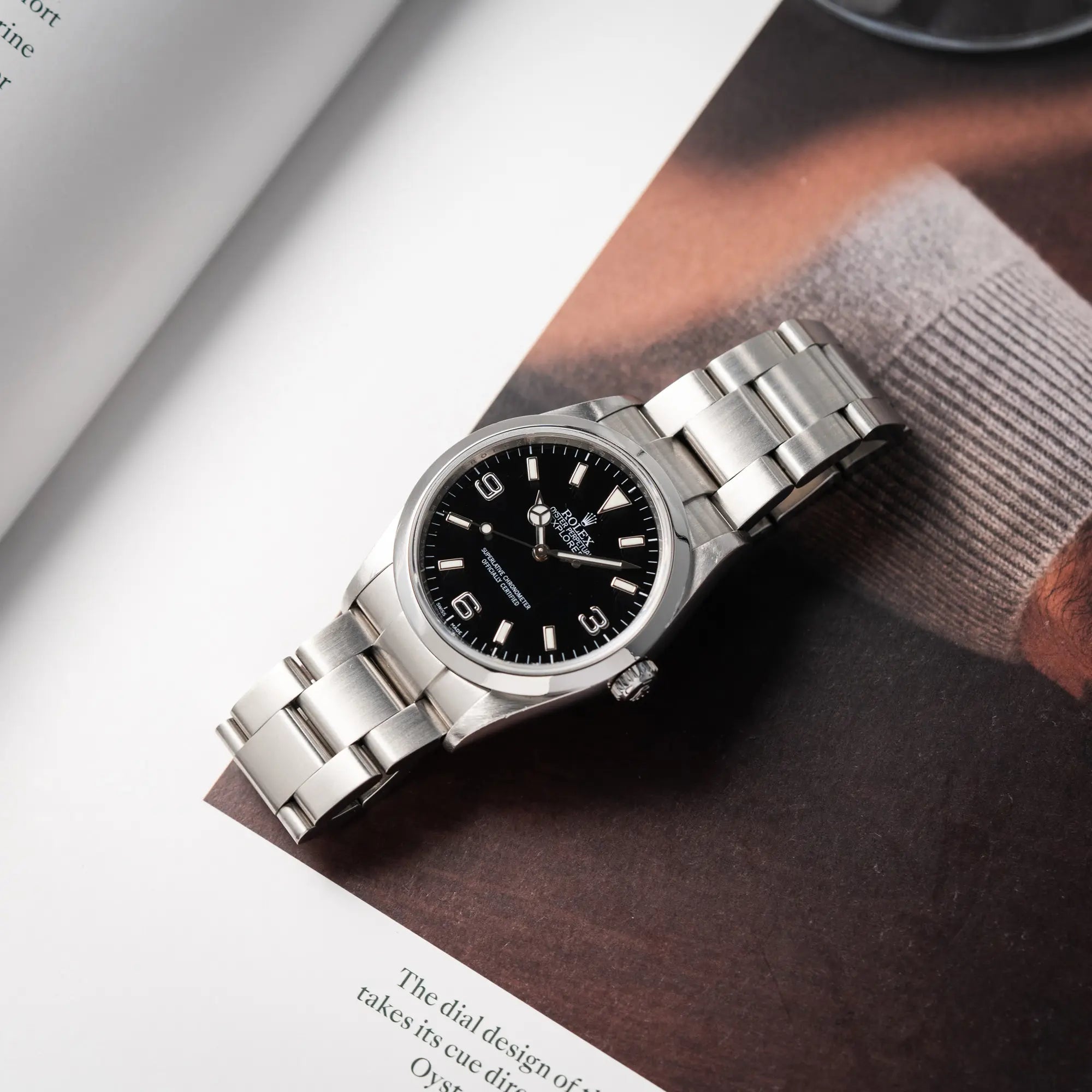 Rolex Explorer 36 der Referenz 114270 mit dem klassischen schwarzen 3-6-9 Zifferblatt liegt flach auf einem Uhrenmagazin