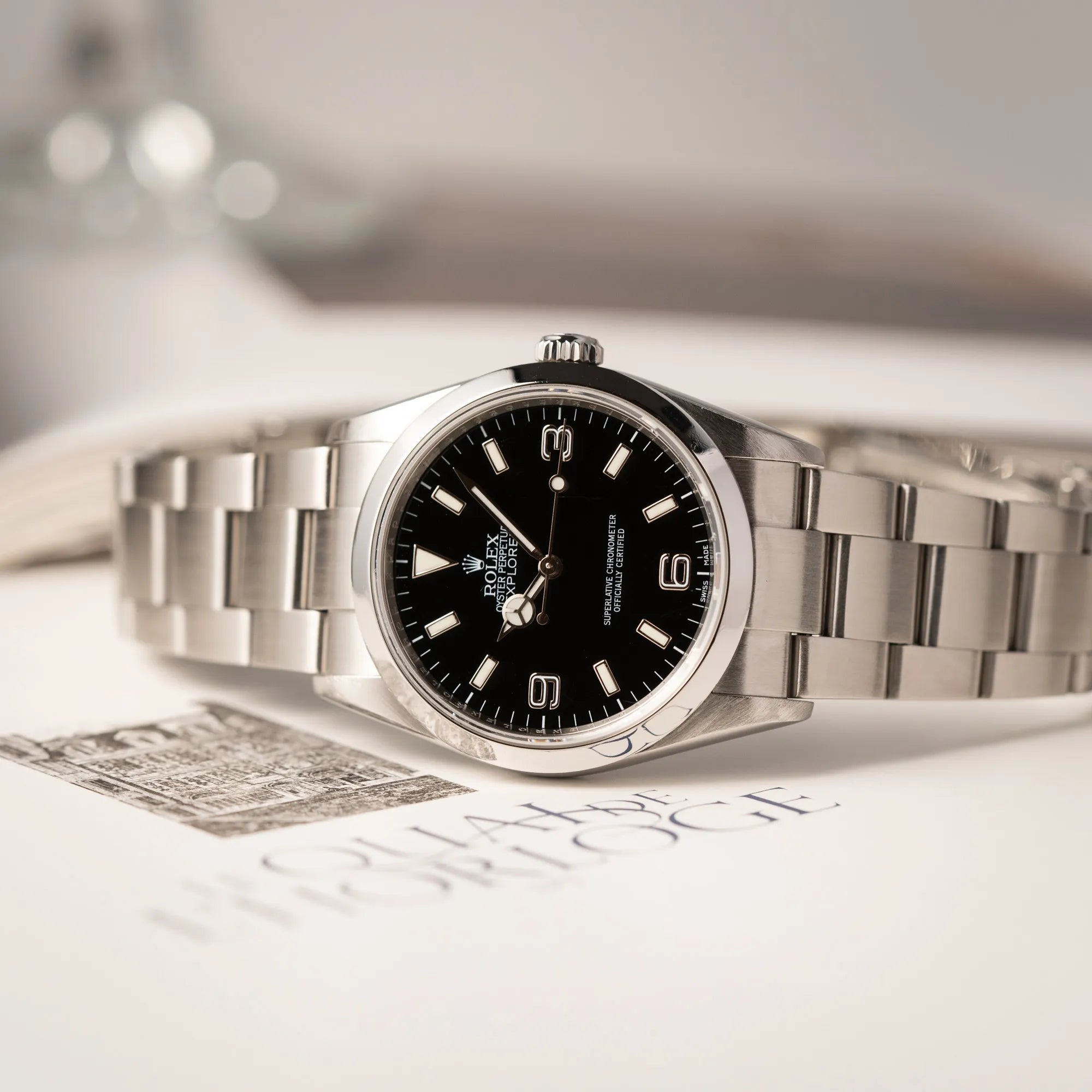 Rolex Explorer 36 der Referenz 114270 mit dem klassischen schwarzen 3-6-9 Zifferblatt liegt seitlich auf der Gehäuseflanke