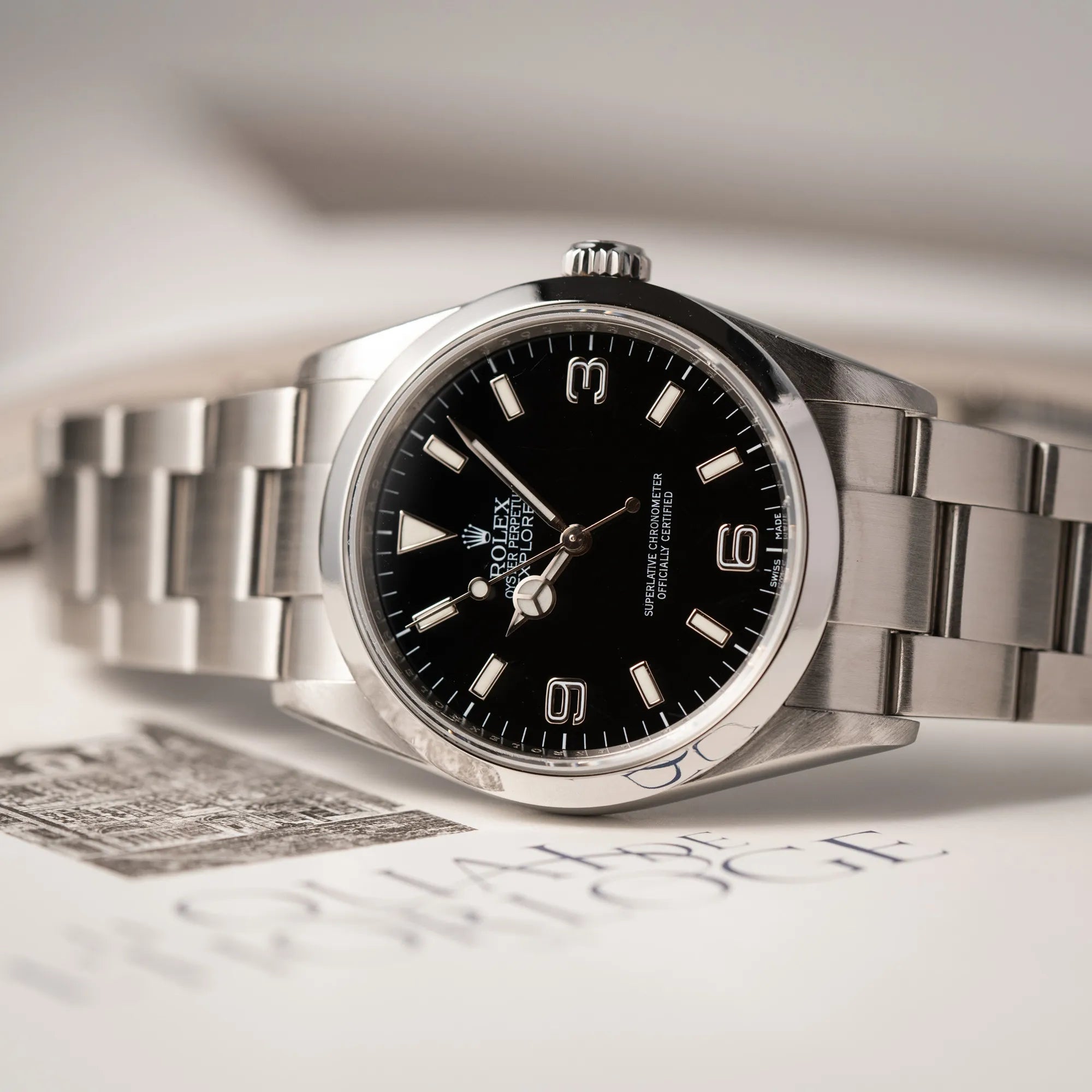 Rolex Explorer 36 der Referenz 114270 mit dem klassischen schwarzen 3-6-9 Zifferblatt liegt auf der seiltichen Gehäuseflanke