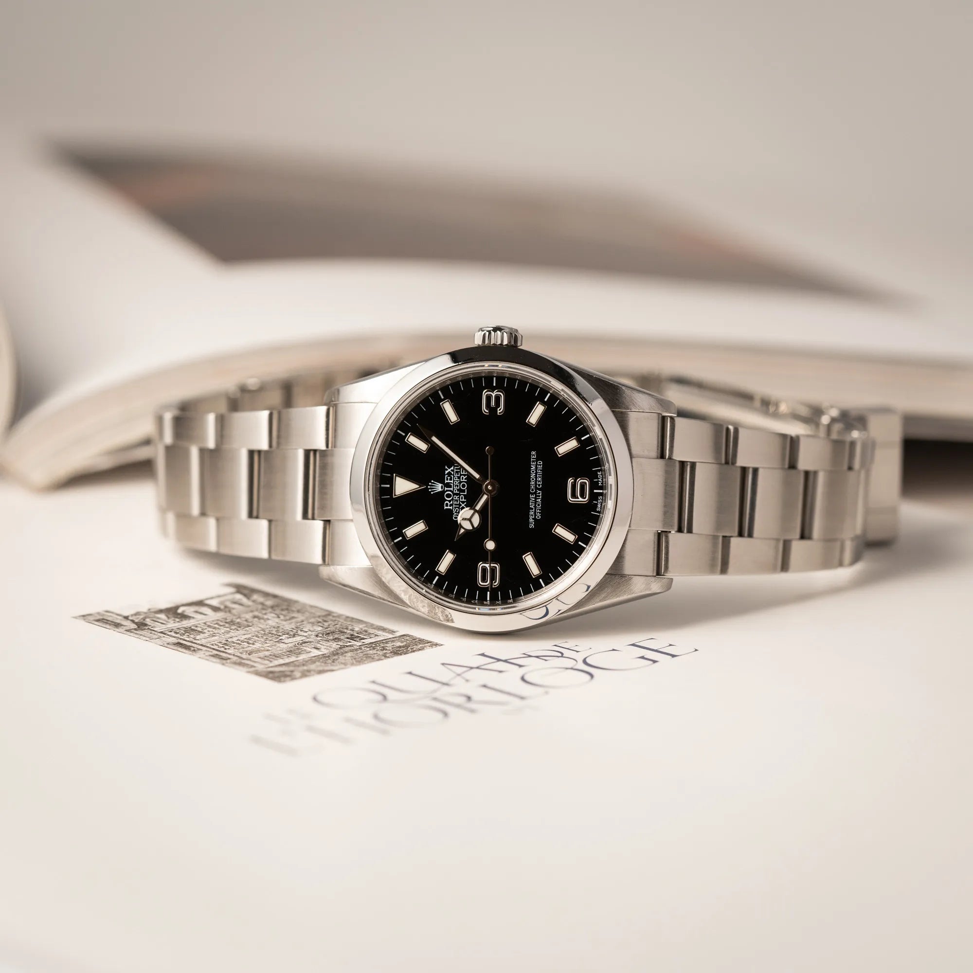 Rolex Explorer 36 der Referenz 114270 mit dem klassischen schwarzen 3-6-9 Zifferblatt liegt auf der seitlichen Gehäuseflanke der Produktfotografie der Rolex Explorer 36 der Referenz 114270 mit dem klassischen schwarzen 3-6-9 Zifferblatt