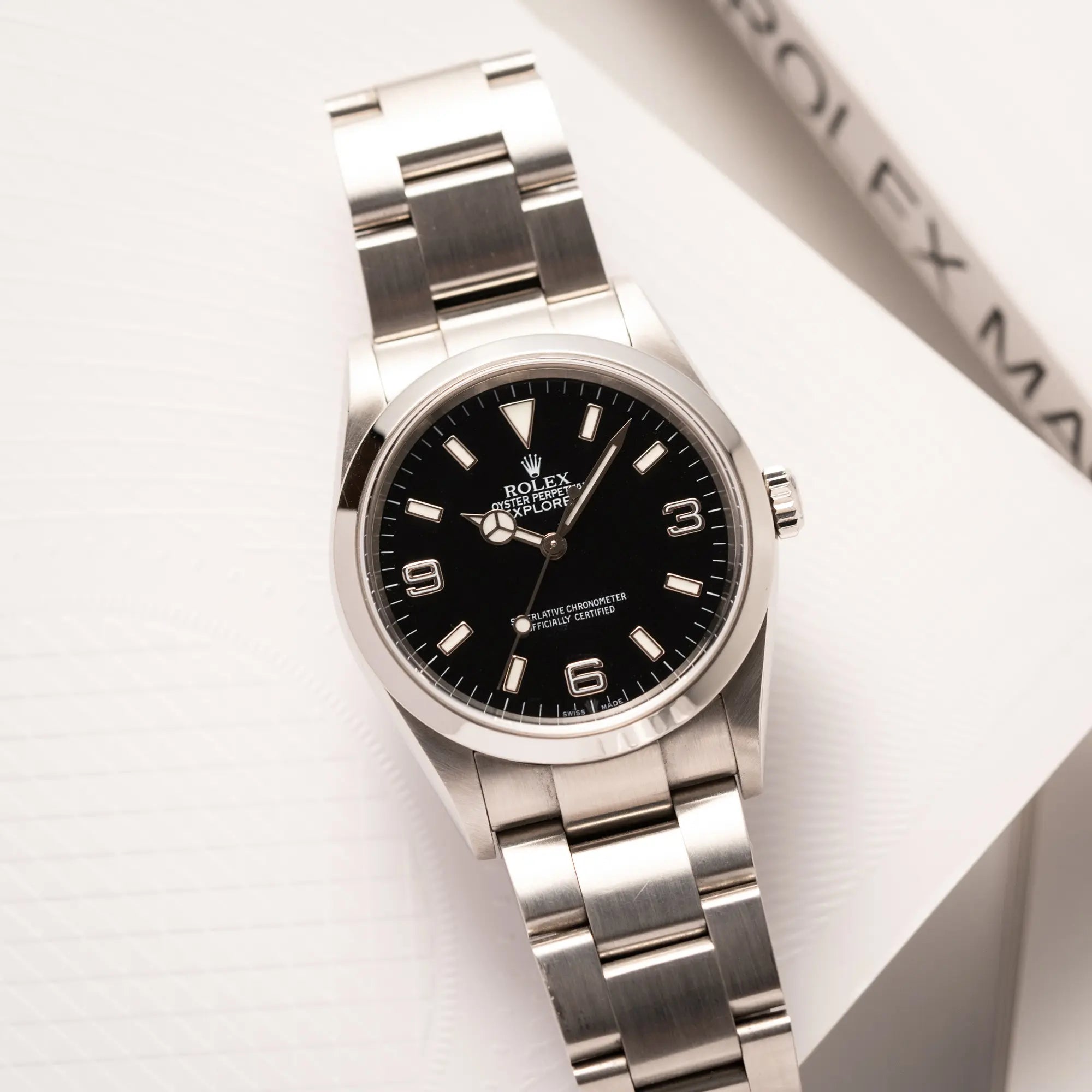 Rolex Explorer 36 der Referenz 114270 mit dem klassischen schwarzen 3-6-9-Explorer-Zifferblatt am Oytser-Stahlband liegt auf einem Uhrenbuch