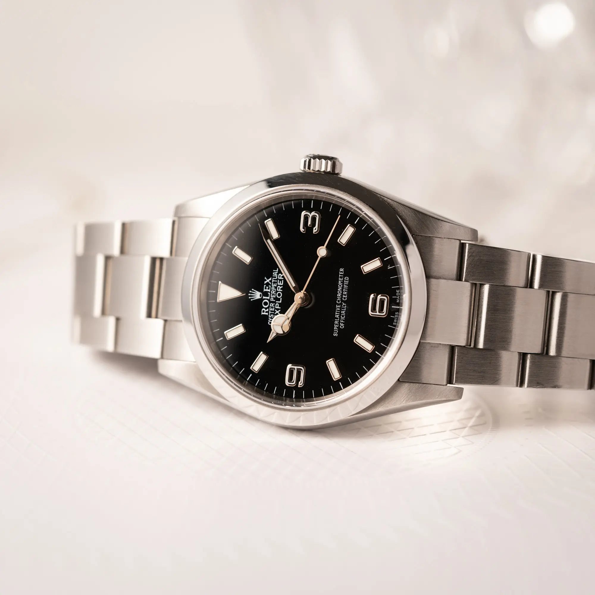 Detailaufnahme der seitlich auf dem Uhrengehuse liegenden Rolex Explorer 36 der Referenz 114270 mit dem klassischen schwarzen 3-6-9-Explorer-Zifferblatt am Oytser-Stahlband
