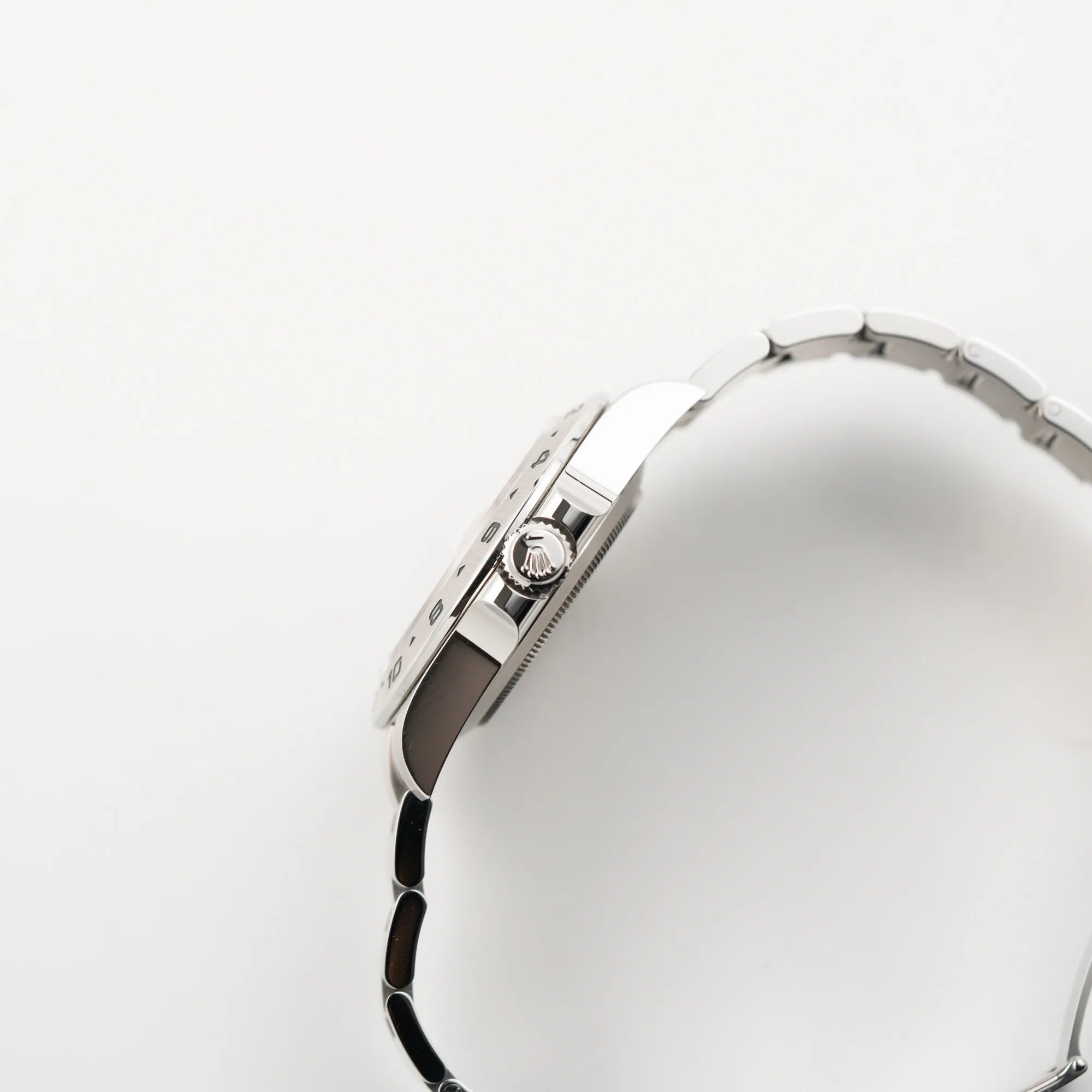 Seitliche Gehäuseflanke mit Blick auf die Aufzugkrone der Rolex Explorer II 216570 aus 2021 mit dem weißen Polar Zifferblatt mit dem typischen orangen GMT-Zeiger in einem sehr guten Zustand