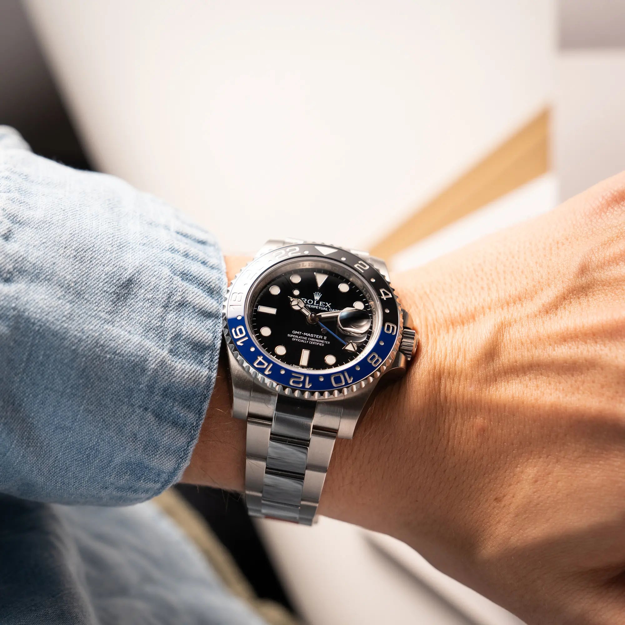 Mann präsentiert die Rolex GMT-Master II der Referenz 116710BLNR mit dem Nickname "Batman" mit der schwarz blauen Keramik-Lünette am Oyster-Stahlband im verklebten Neuzustand  an seinem Handgelenk