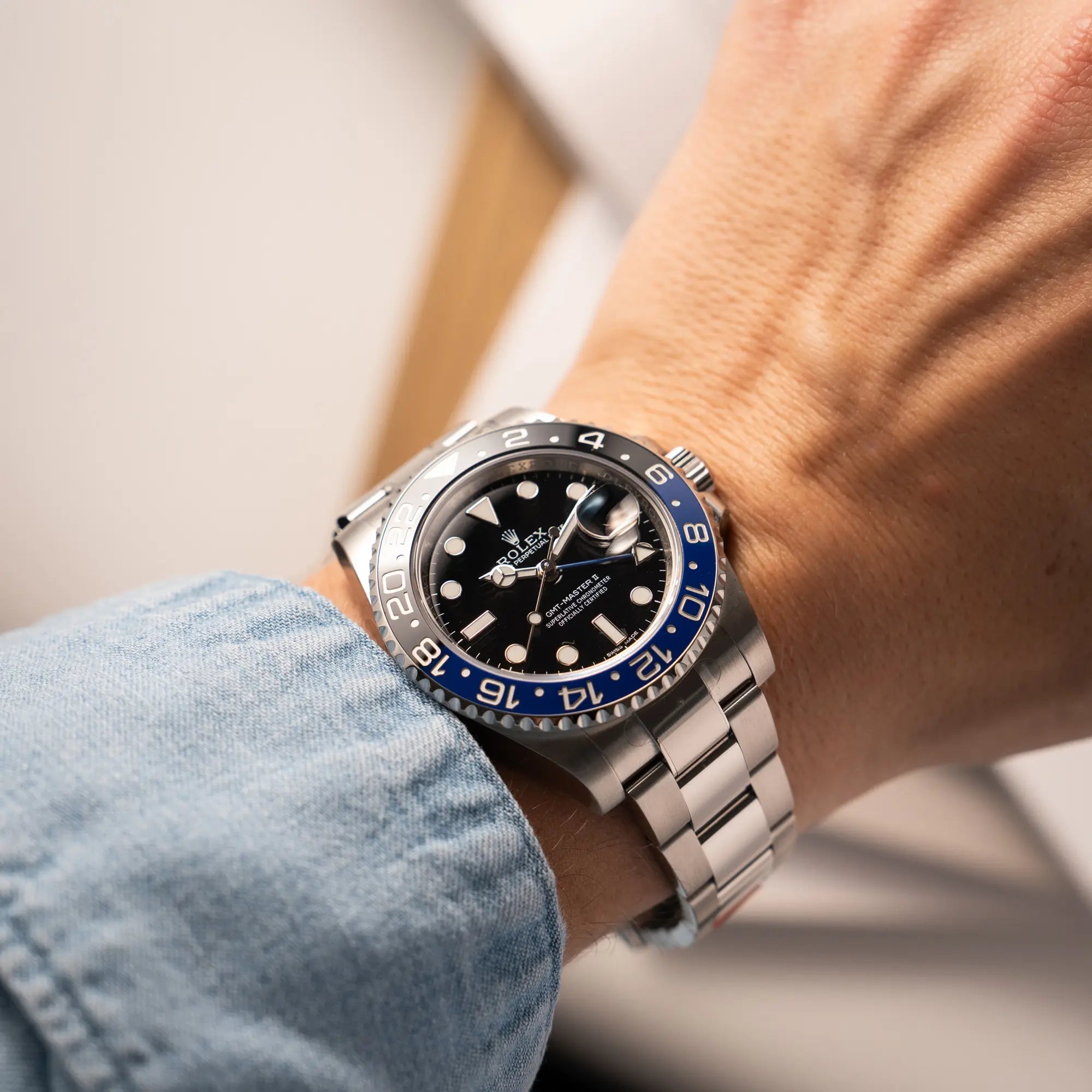 Mann trägt die Rolex GMT-Master II der Referenz 116710BLNR mit dem Nickname "Batman" mit der schwarz blauen Keramik-Lünette am Oyster-Stahlband im verklebten Neuzustand an seinem Handgelenk