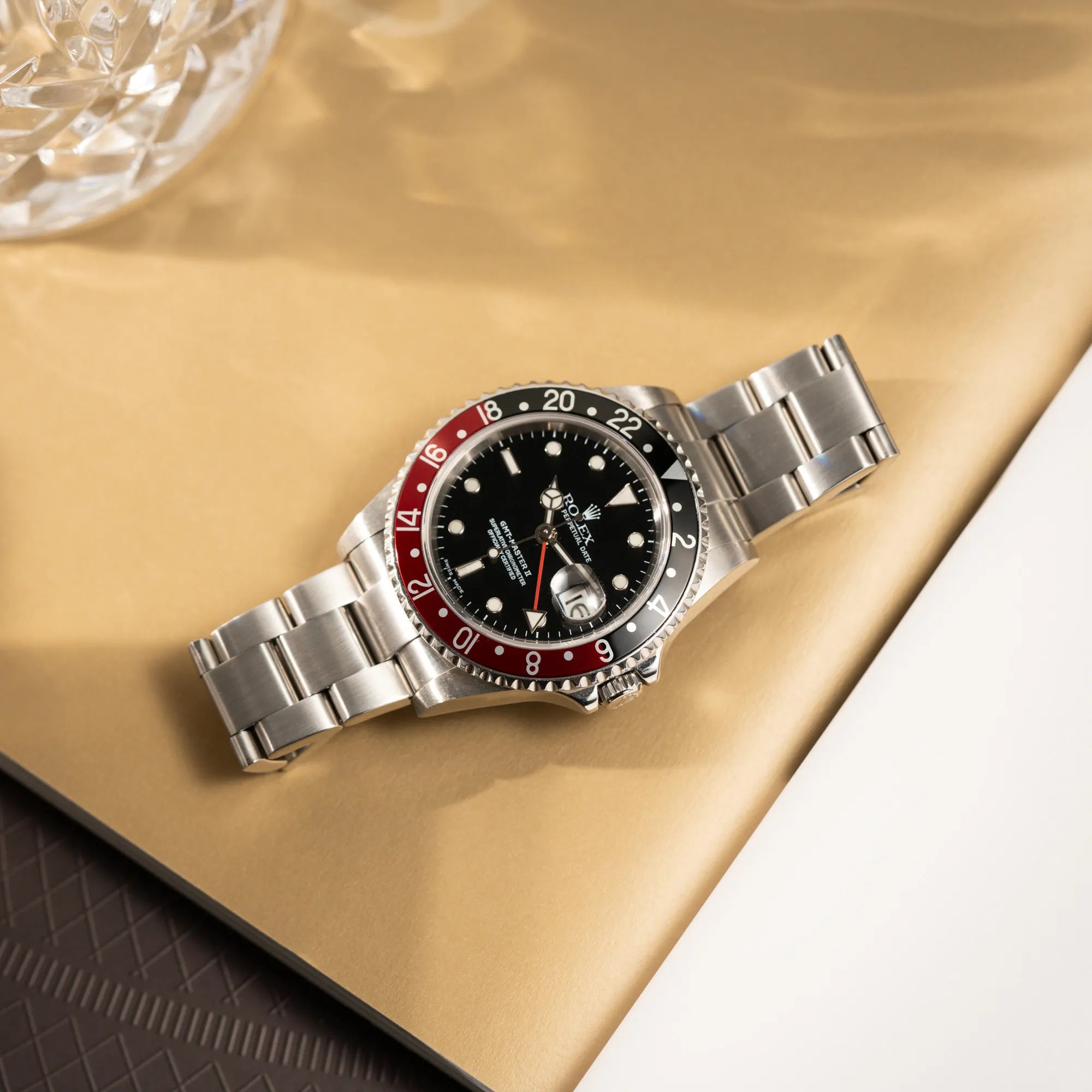 Produktfotografie der flach auf dem Band liegenden Rolex GMT-Master II 16710 mit der schwarz-roten "Coke" Aluminium-Lünetten-Einlage aus 2003 am Oyster Stahlband