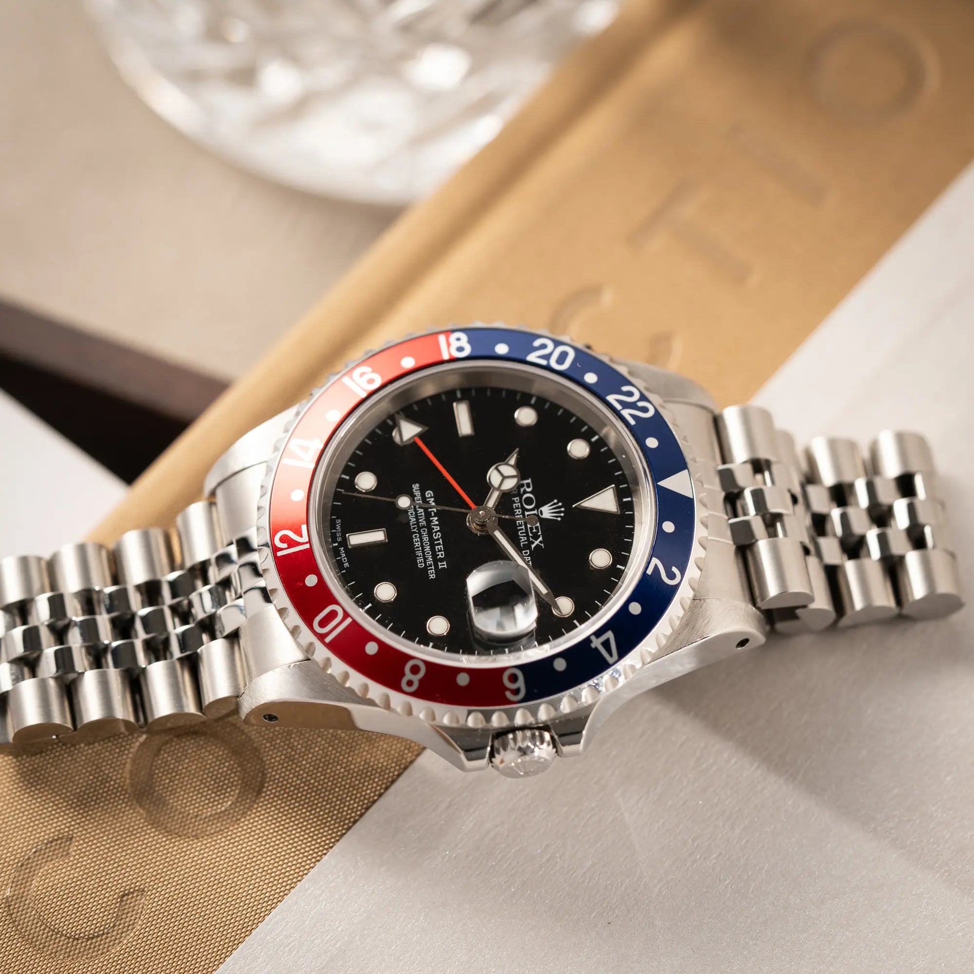 Produktfotografie der flach auf einem Buch liegenden Rolex GMT-Master II 16710 mit der blau-roten Pepsi-Lünette am Jubilee-Armband 