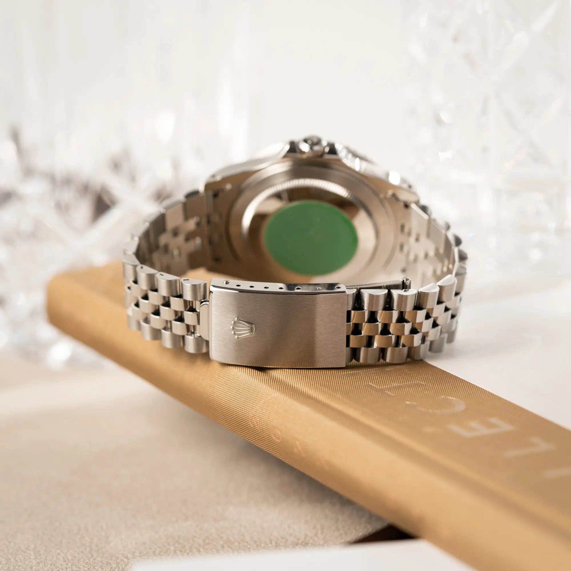 Produktfotografie zeigt den neuwertigen Zustand der Schliesse am Jubilee-Armband und den grünen Sticker auf dem Gehäuseboden der Rolex GMT-Master II 16710 mit der blau-roten Pepsi-Lünette