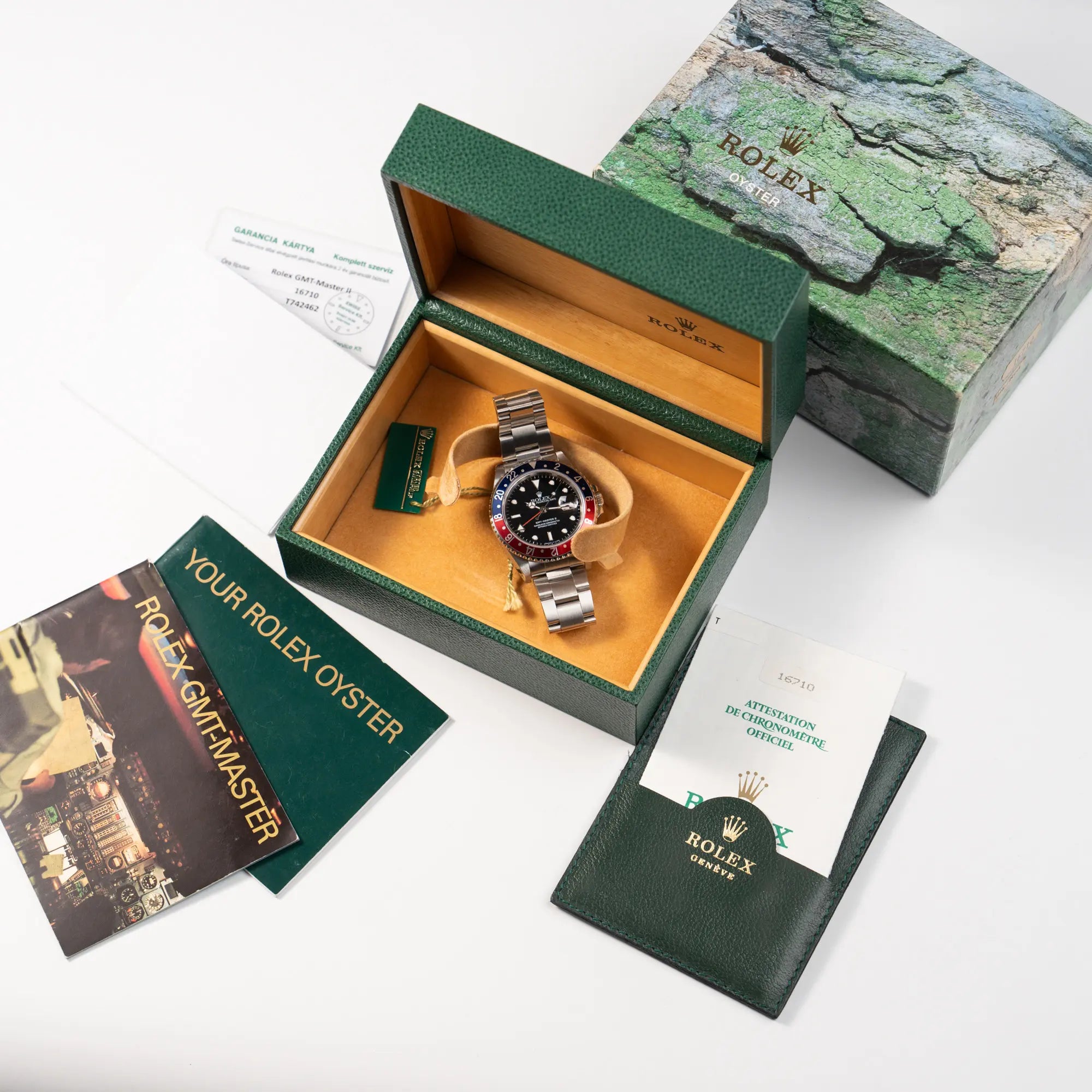 Rolex GMT Master 2 der Referenz 16710 aus der T-Serie mit blau-roter Pepsi-Lünette zusammen mit dem Lieferumfang, bestehend aus originaler Box mit Umkarton, Booklets, Hangtags, Service-Beleg aus 2025 und originalen Papieren