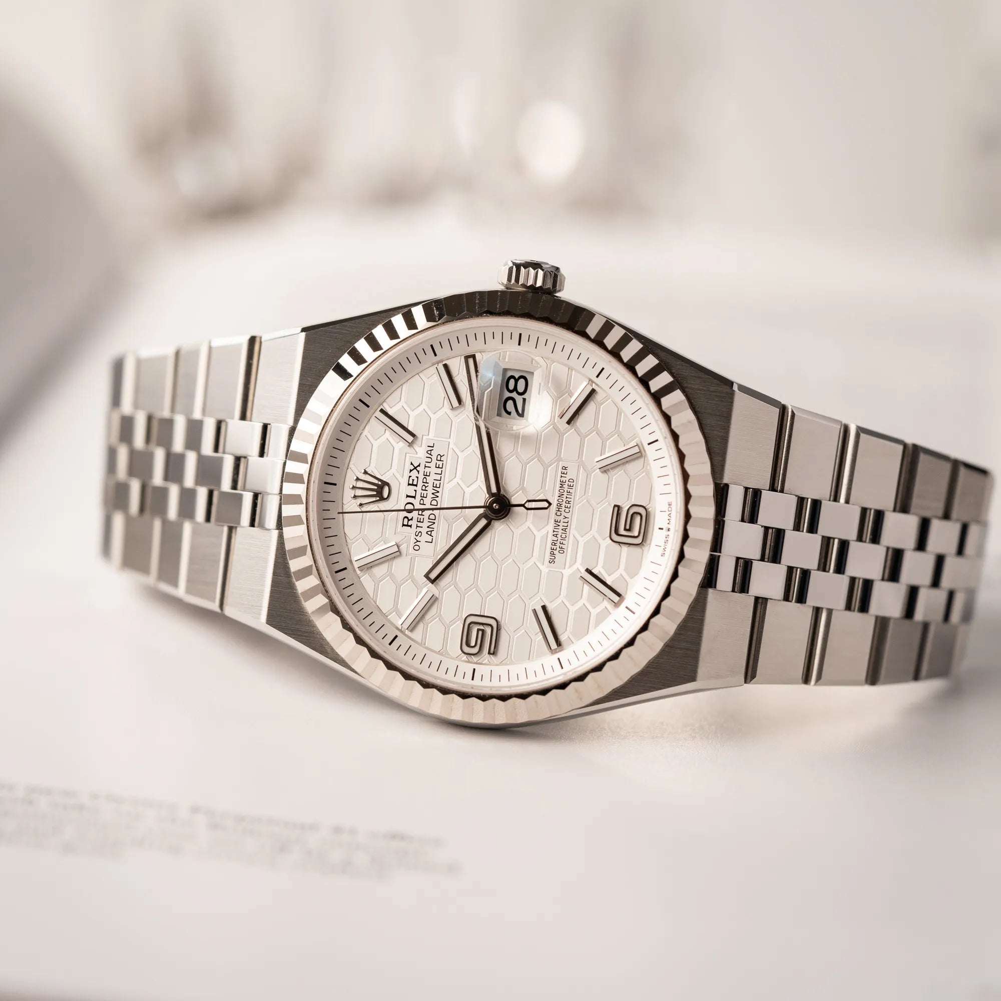 Produktfotografie als Titelbild für die Rolex Land-Dweller 40 der Referenz 127334 im neuwertigen Zustand mit dem weißen Zifferblatt in Waben-Struktur am neuen Flat-Jubilee-Armband