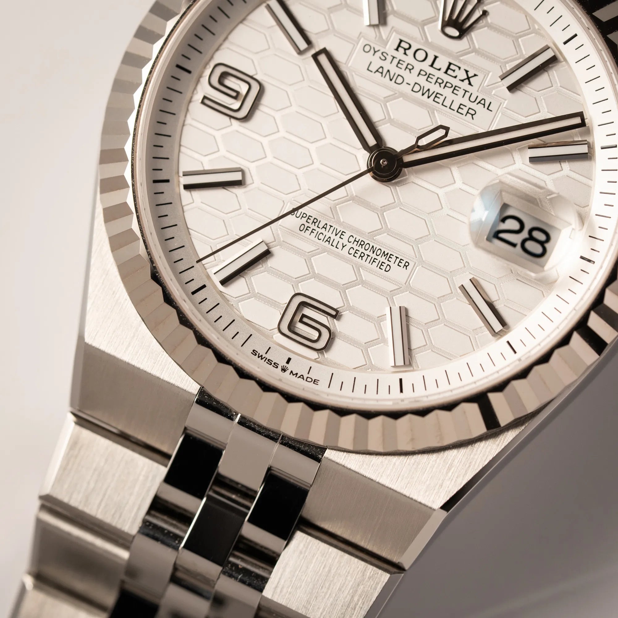 Detailaufnahme der Rolex Land-Dweller 40 der Referenz 127334 im neuwertigen Zustand mit dem weißen Zifferblatt in Waben-Struktur am neuen Flat-Jubilee-Armband bei 6 Uhr